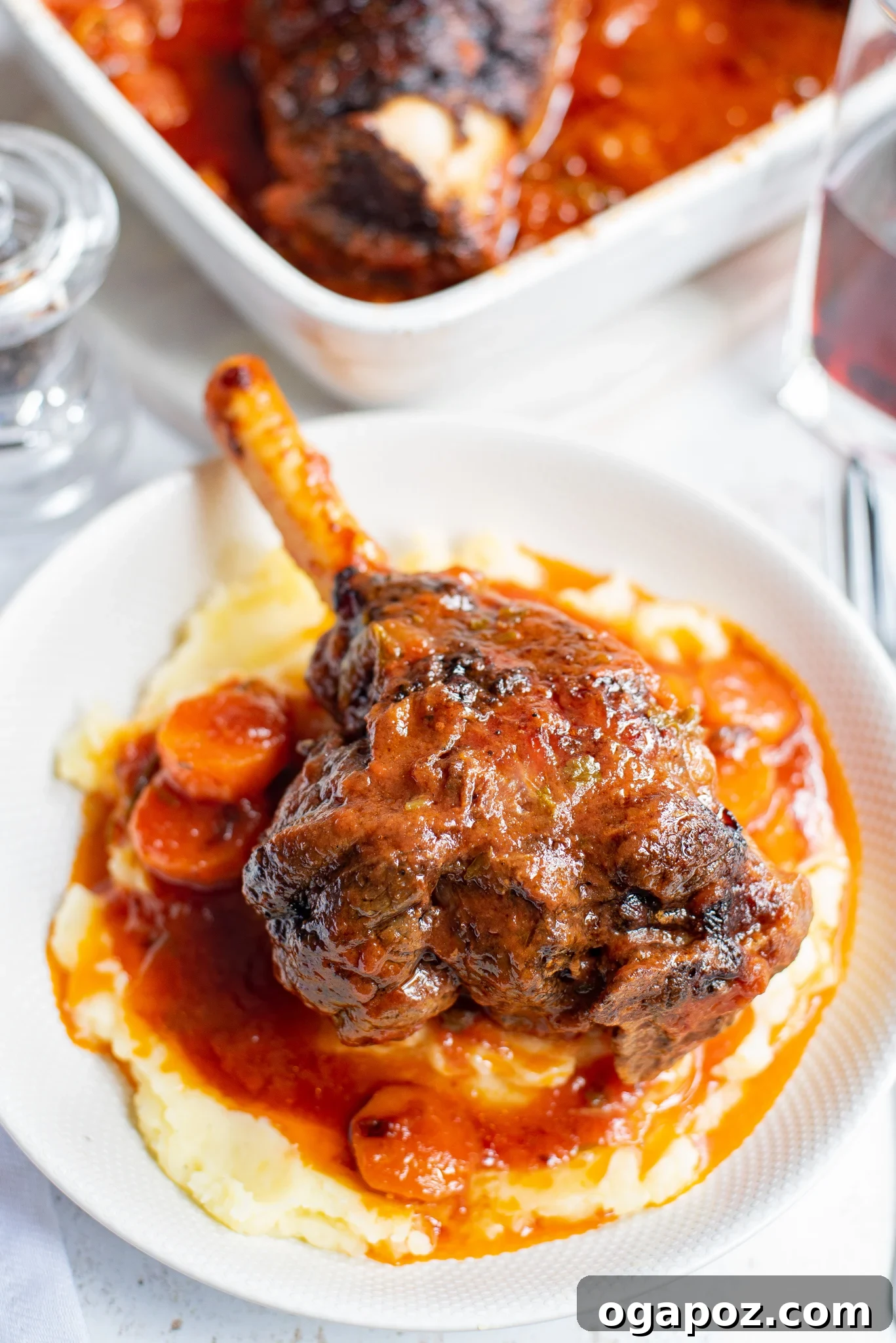 Fall-Off-The-Bone Braised Lamb Shanks 2 Braised Lamb Shank Recipe in a white bowl, garnished with fresh herbs.