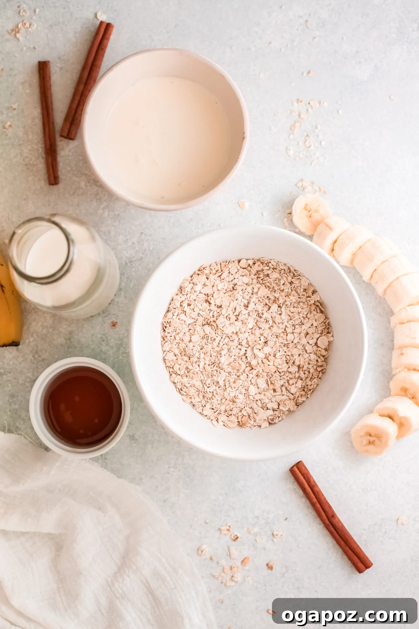 Quick & Healthy Oat Smoothies 3 A selection of oat smoothie ingredients laid out: bananas, oats, milk, Greek yogurt, maple syrup, cinnamon, and nutmeg.