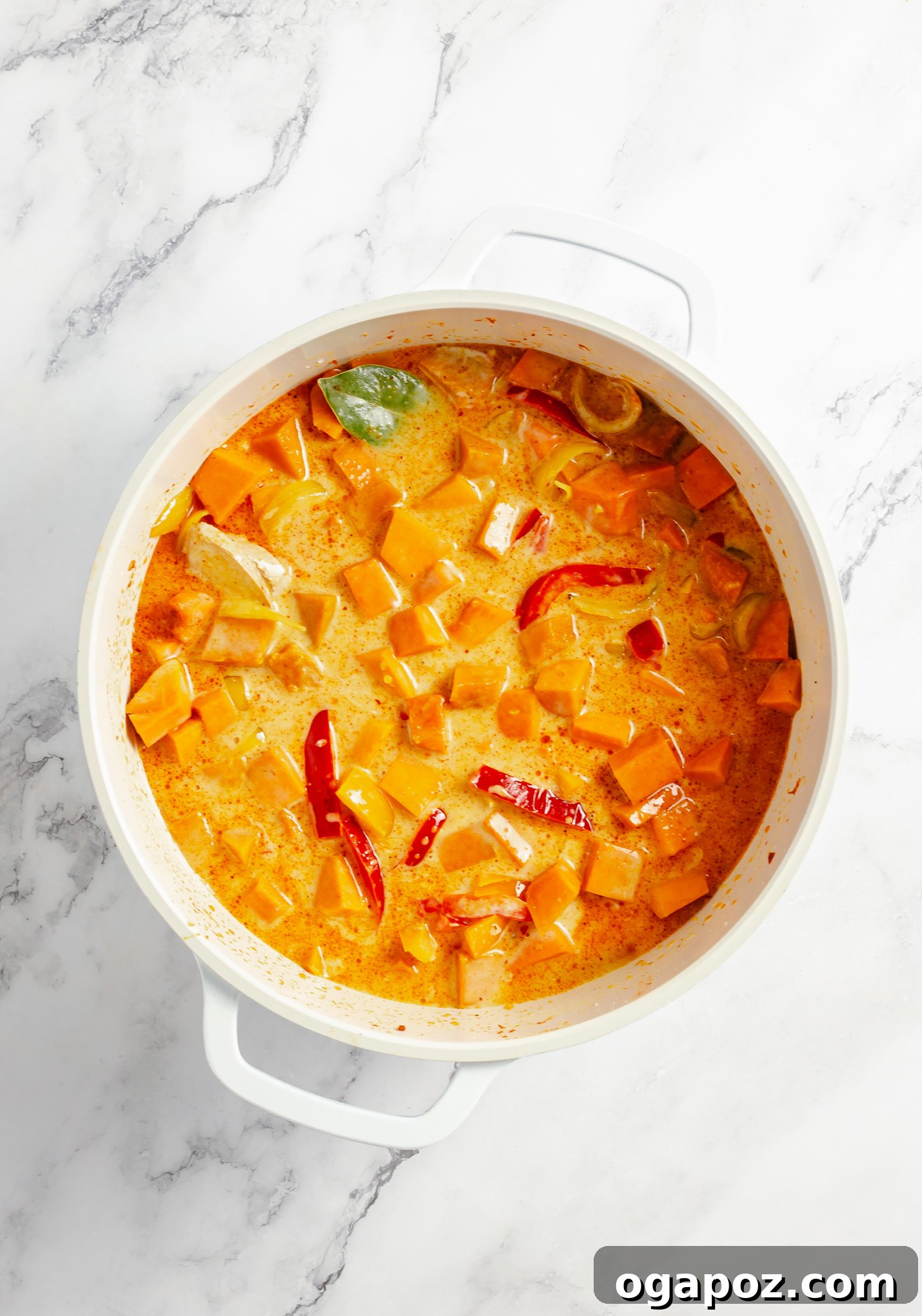 Pumpkin pieces and broth simmering in a large pot for curry.