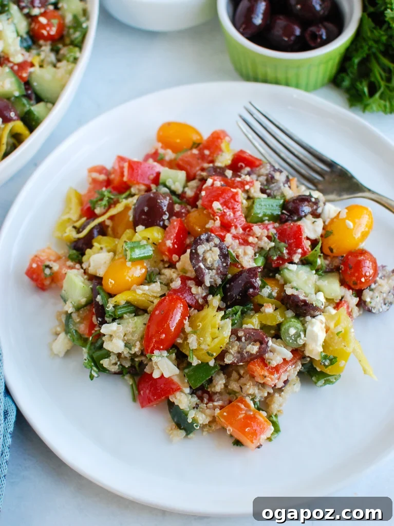 Santorini Sunset Quinoa Salad 4 A hand using a fork to scoop a portion of Greek Quinoa Salad from a white bowl