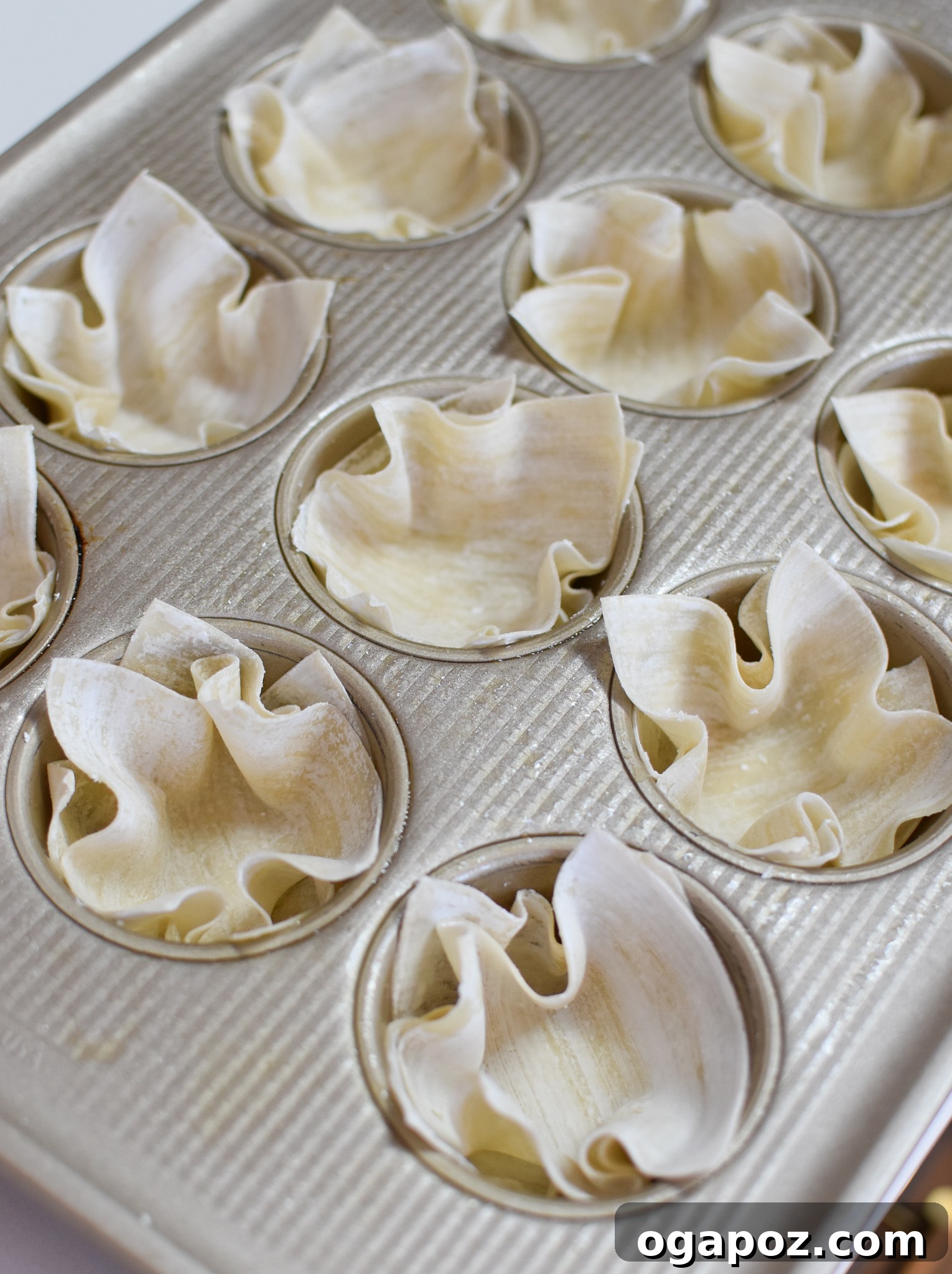 Mediterranean Quiche Parcels 6 Mediterranean Quiche Wontons baking in a muffin tin, showing their golden edges.