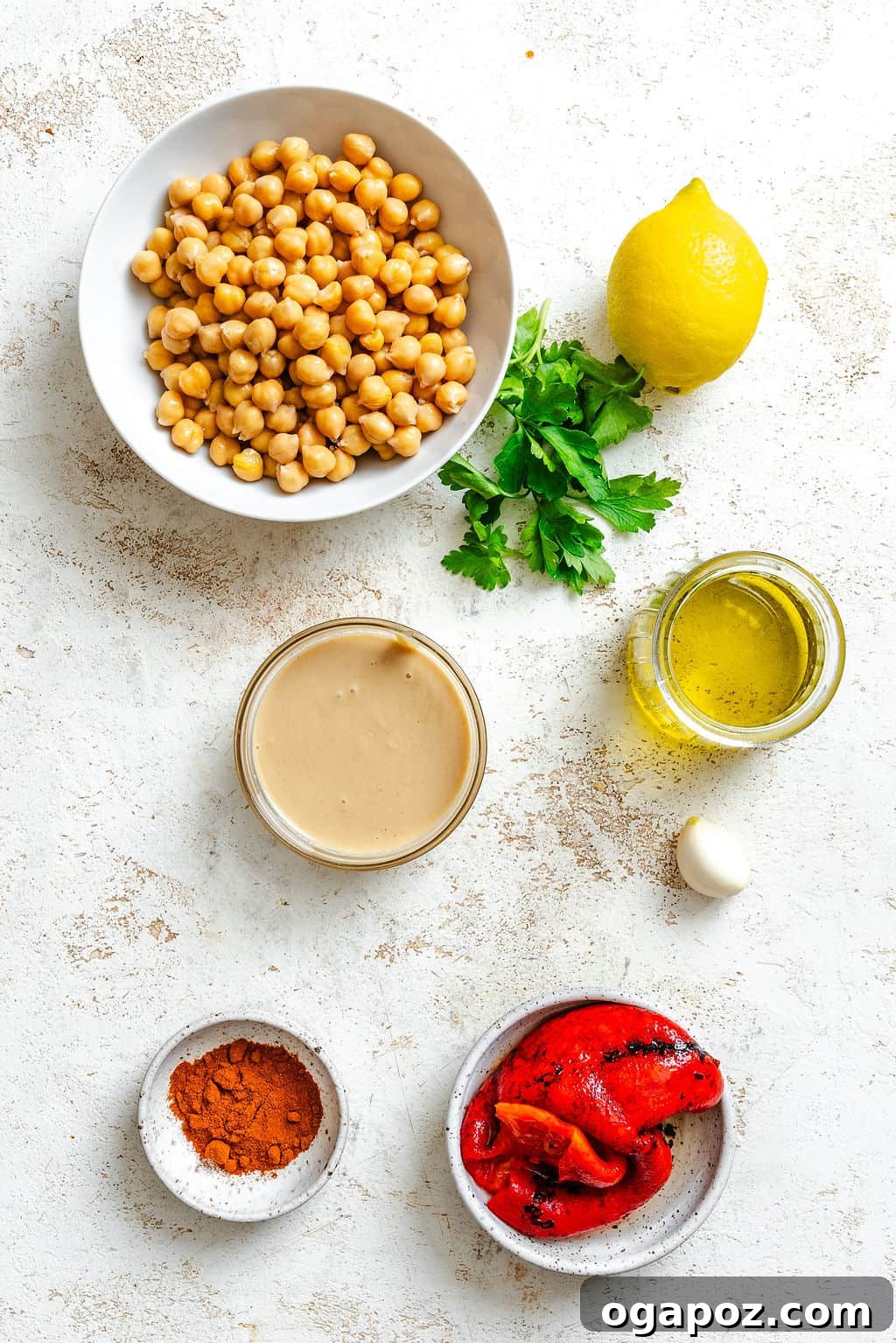 Arrangement of fresh ingredients for Roasted Red Pepper Hummus recipe, including chickpeas, lemons, tahini, and jarred roasted red peppers