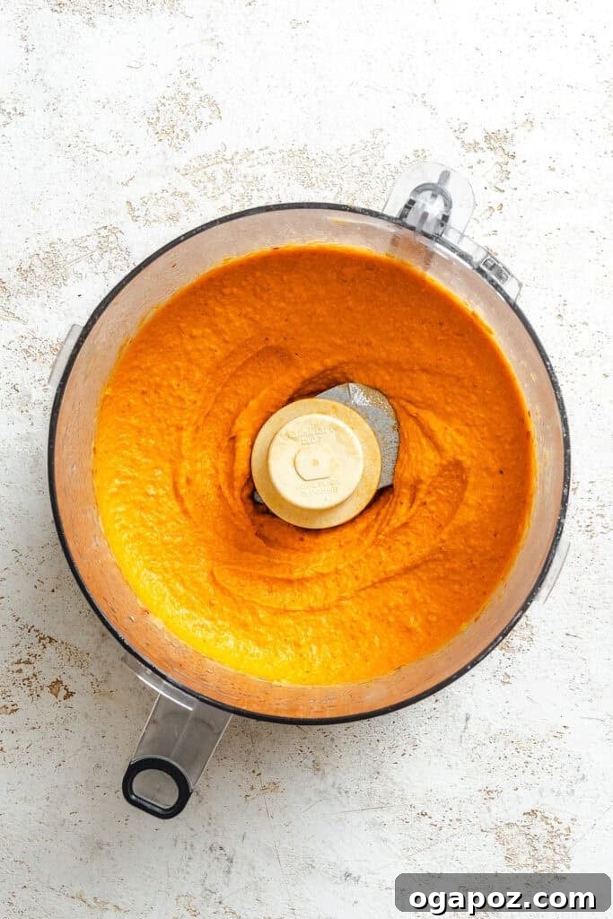 Smooth, pureed Roasted Red Pepper Hummus inside a food processor bowl
