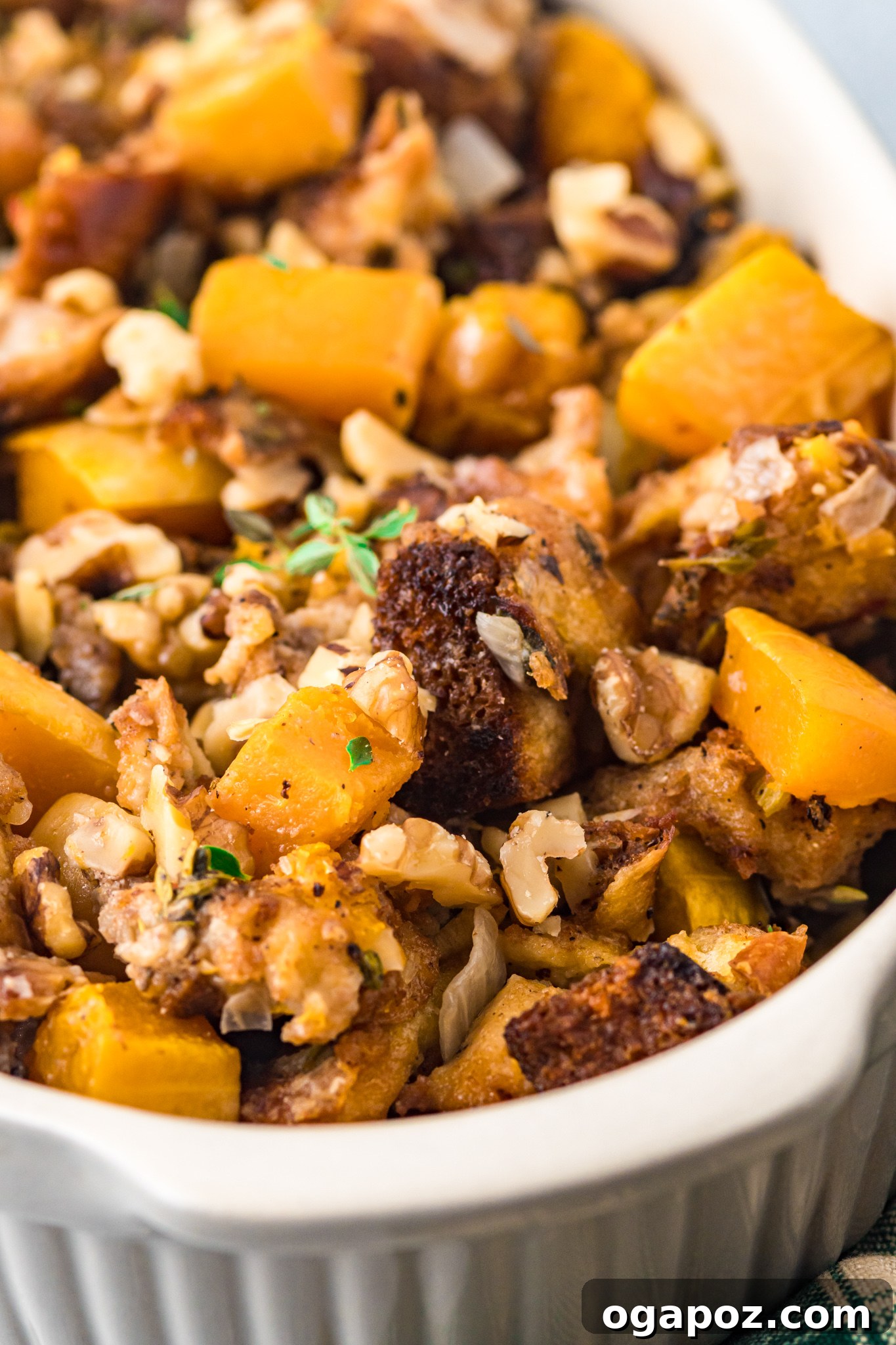 Sweet and Savory Butternut Squash Stuffing 4 Close-up view of baked Butternut Squash Stuffing in a casserole dish, garnished with fresh thyme sprigs and ready to serve.