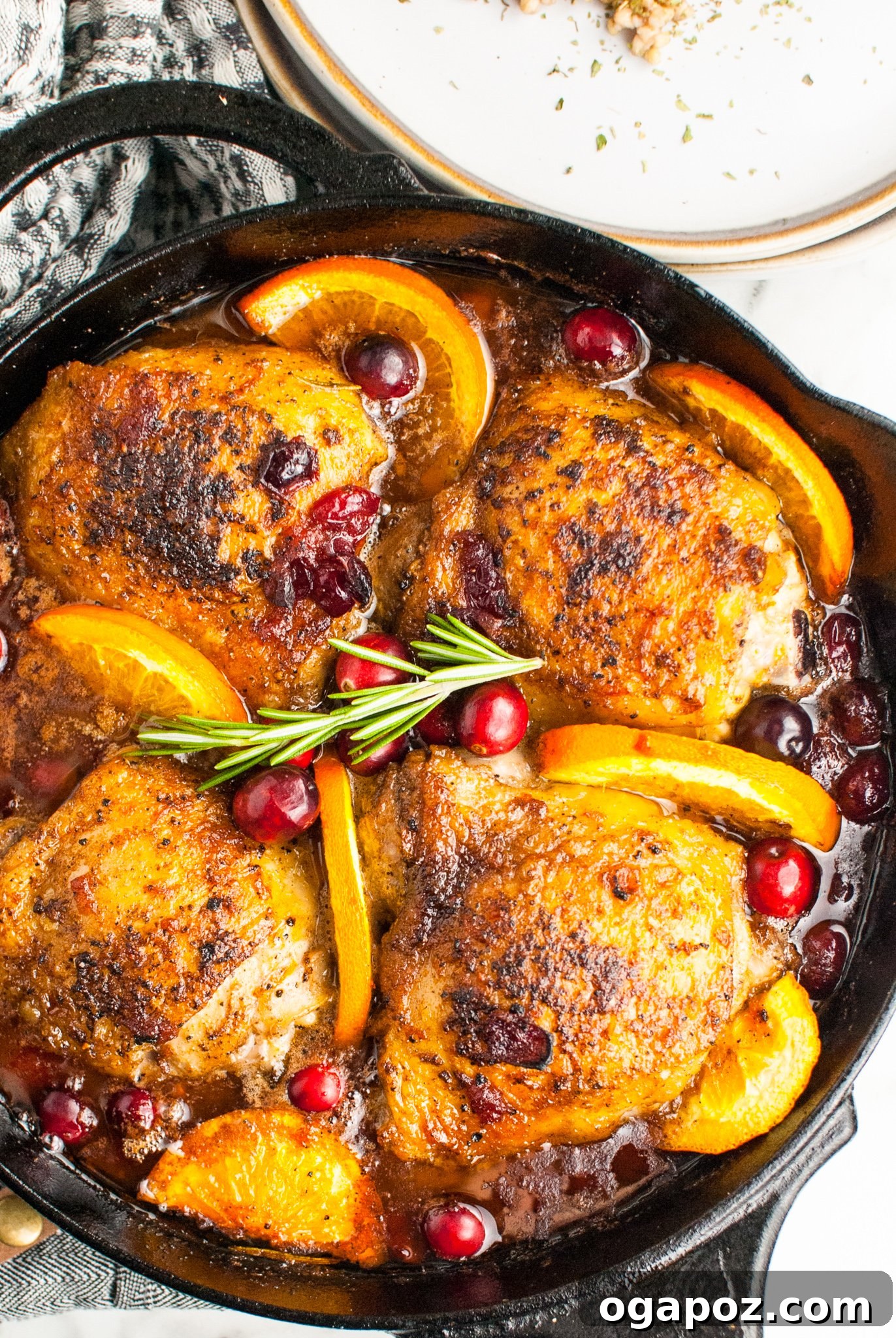 Effortless Cranberry Glazed Chicken Thighs 2 Easy Baked Chicken Thighs in a cast iron skillet, golden brown and glistening with glaze.