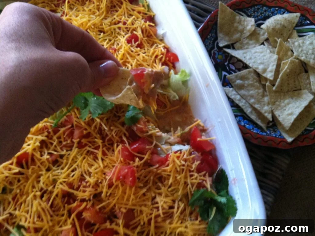 Delicious Seven Layer Dip Skinny Seven Layer Dip served in a large dish with colorful layers clearly visible, ready for serving with tortilla chips.