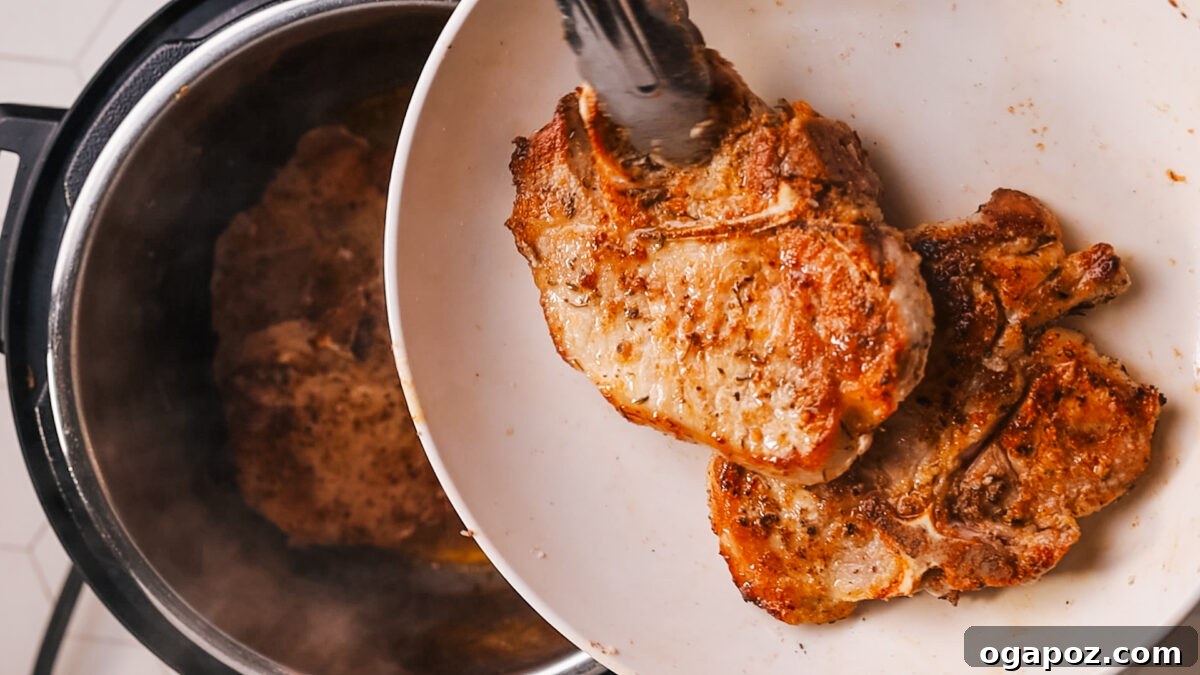 Fork Tender Instant Pot Pork Chops and Simple Gravy 7 Cooked pork chops being transferred to a plate after pressure cooking.