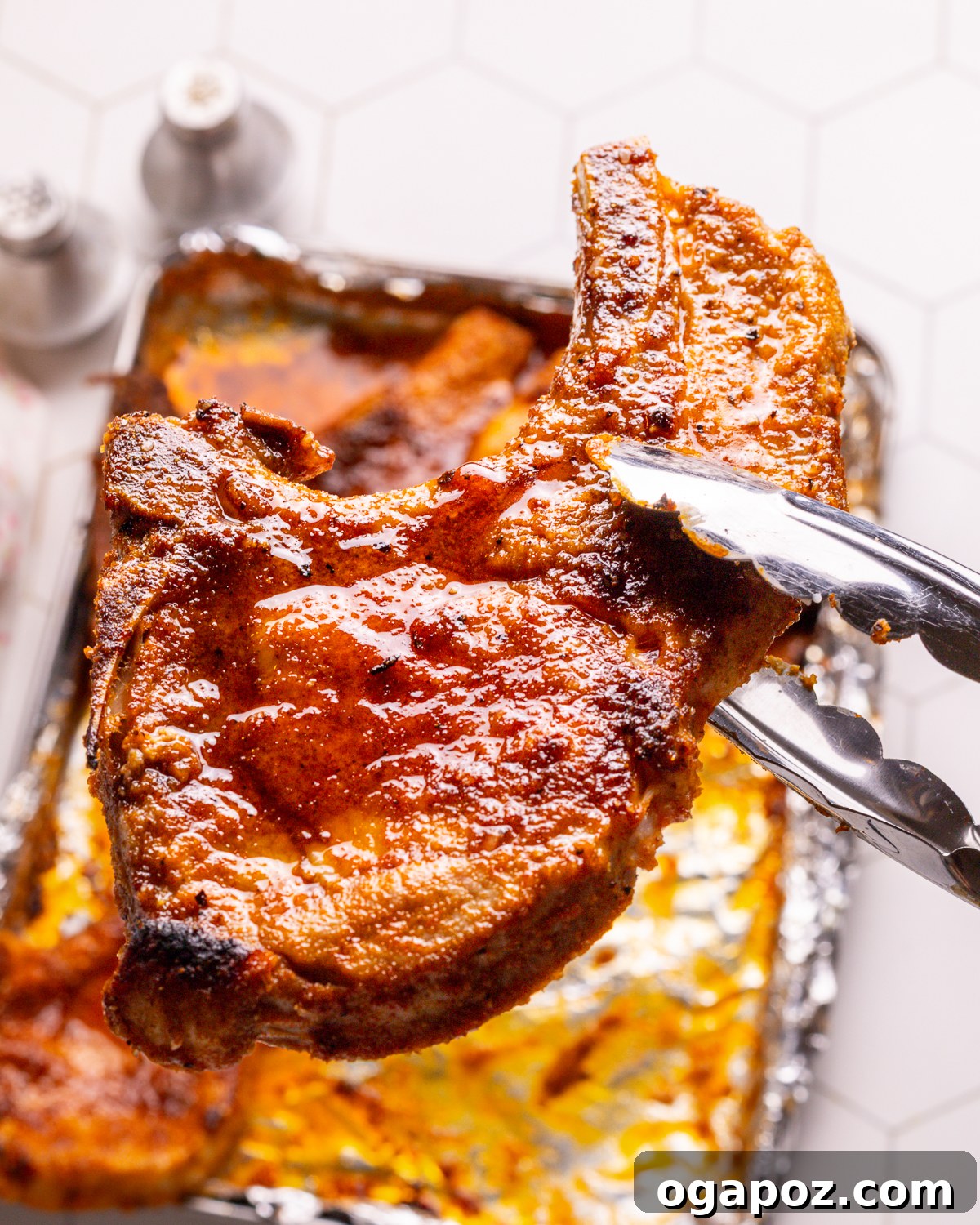 Baked pork chop held with tongs.