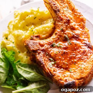 Baked pork chops on a plate with mashed potatoes and salad.