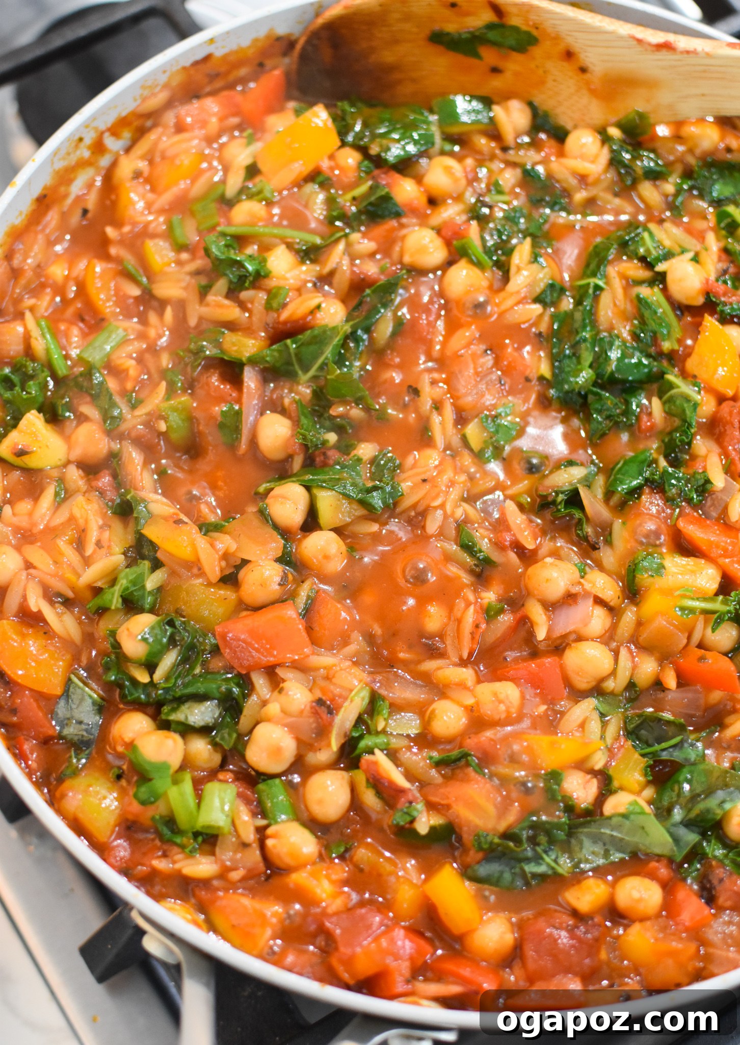 A close-up of Mediterranean Orzo Pasta with kale and chickpeas simmering in the pan.