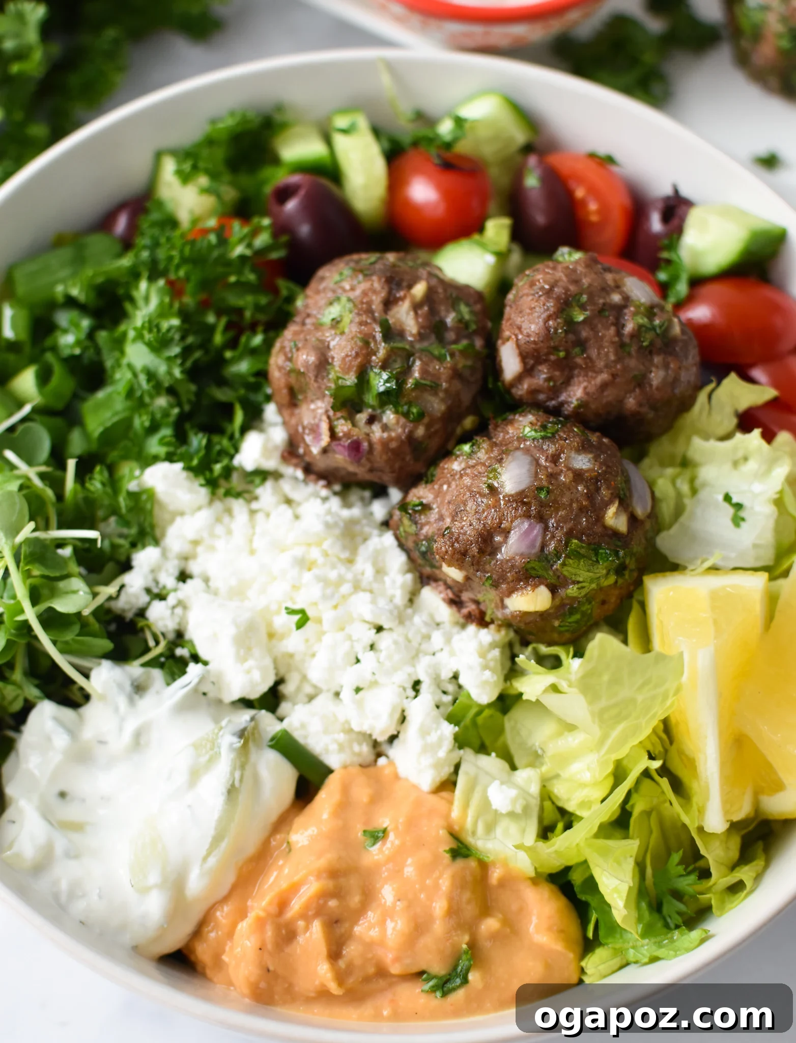 Succulent Mediterranean Baked Beef Meatballs 2 A vibrant hummus bowl featuring golden-brown Mediterranean Baked Beef Meatballs, fresh parsley, and a drizzle of olive oil, showcasing a healthy and flavorful meal.