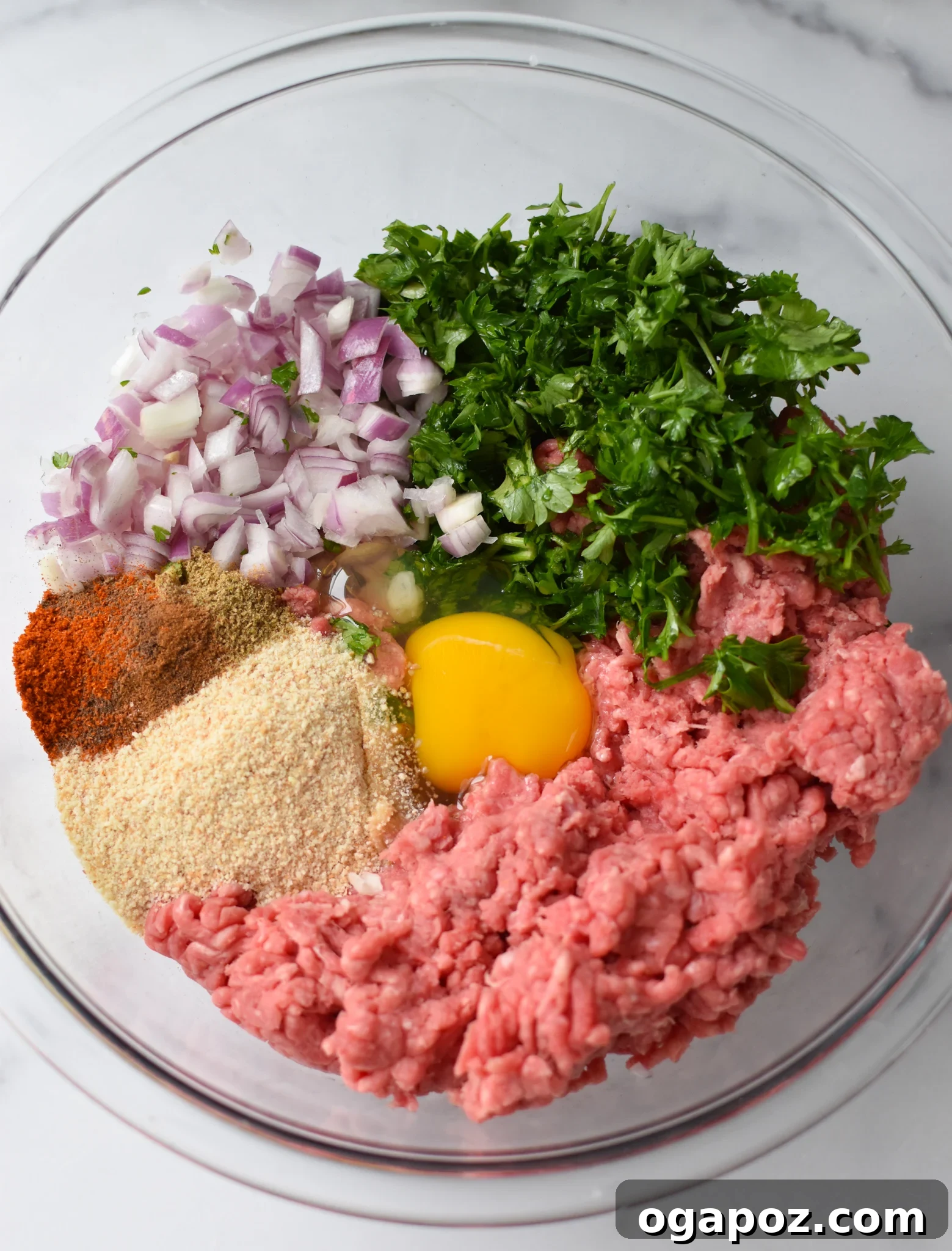Succulent Mediterranean Baked Beef Meatballs 5 Various Mediterranean Baked Beef Meatball ingredients in a mixing bowl, showcasing the herbs and spices before the ground beef is added.