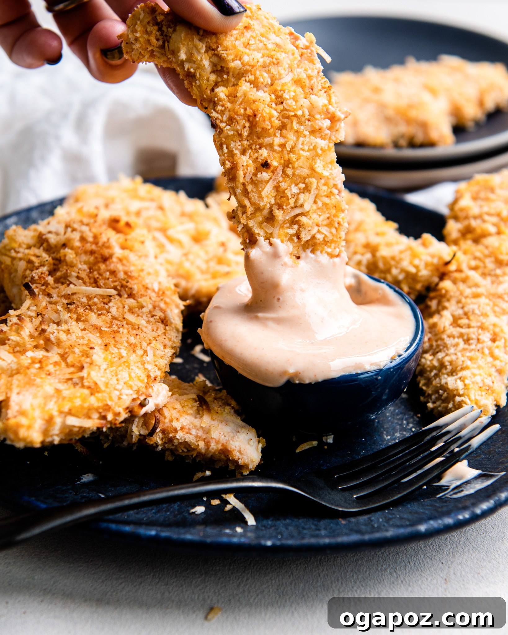 Air-Fried Crispy Coconut Chicken Strips 7 Air Fryer Coconut Chicken Tenders served with sauce in a bowl.
