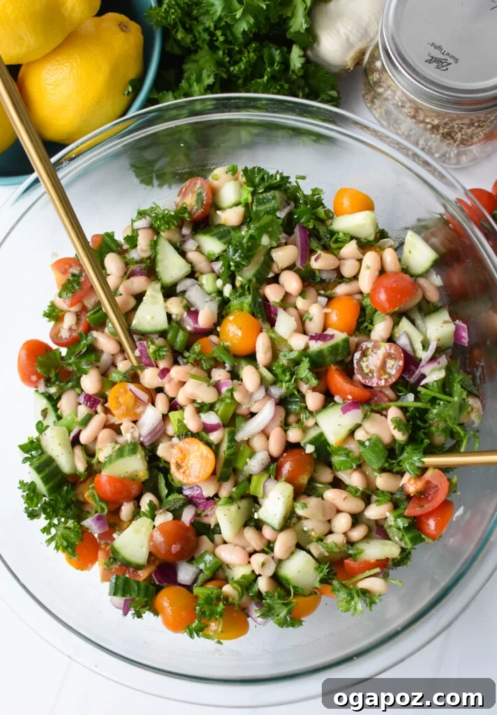 Sun-Drenched Mediterranean White Bean Salad 6 Mediterranean White Bean Salad with gold serving spoons. A bowl of salad ready to be served.