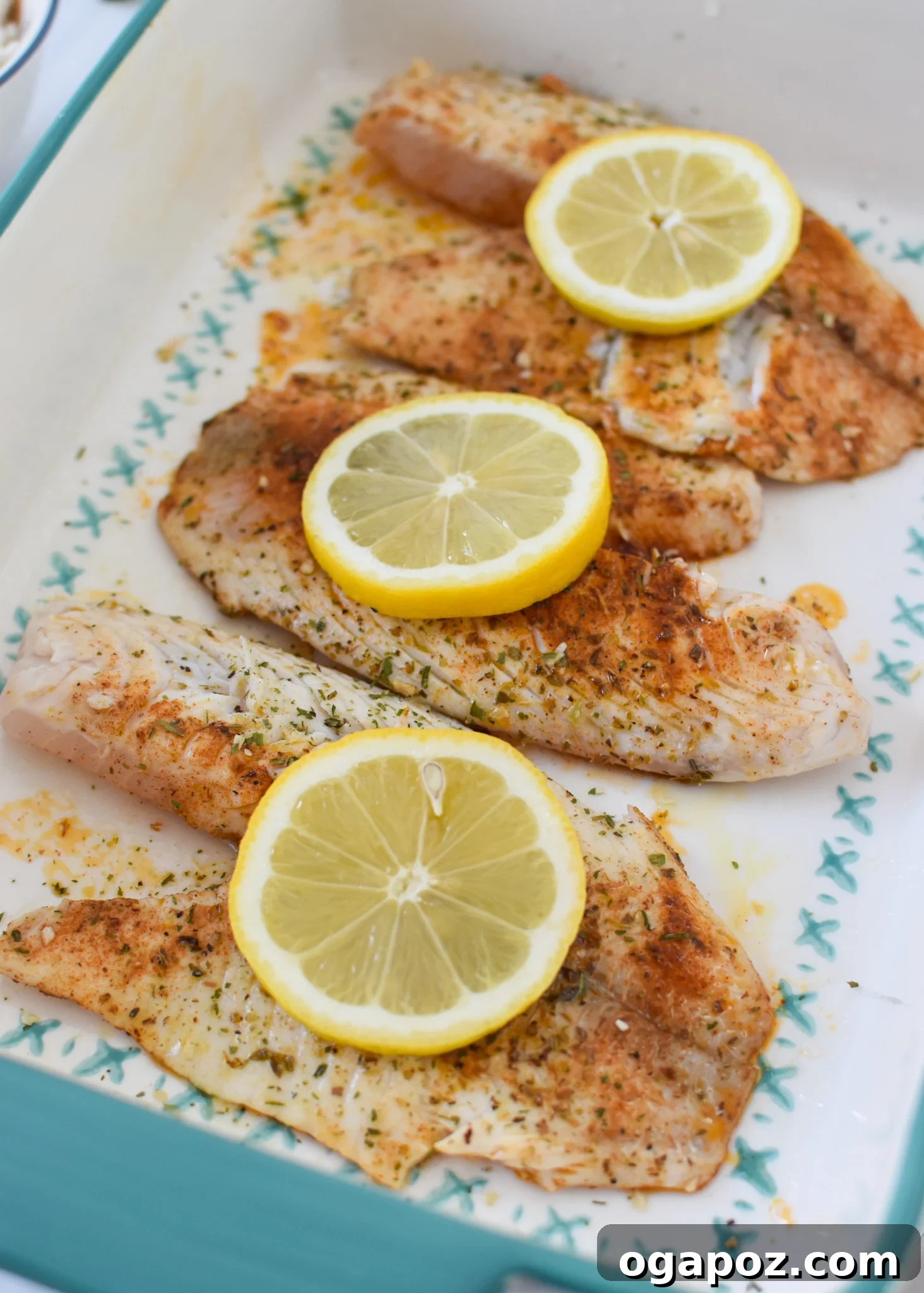 Lemon Herb Greek Tilapia Bake 6 Greek Baked Tilapia in a pan with lemon slices, ready for the oven.