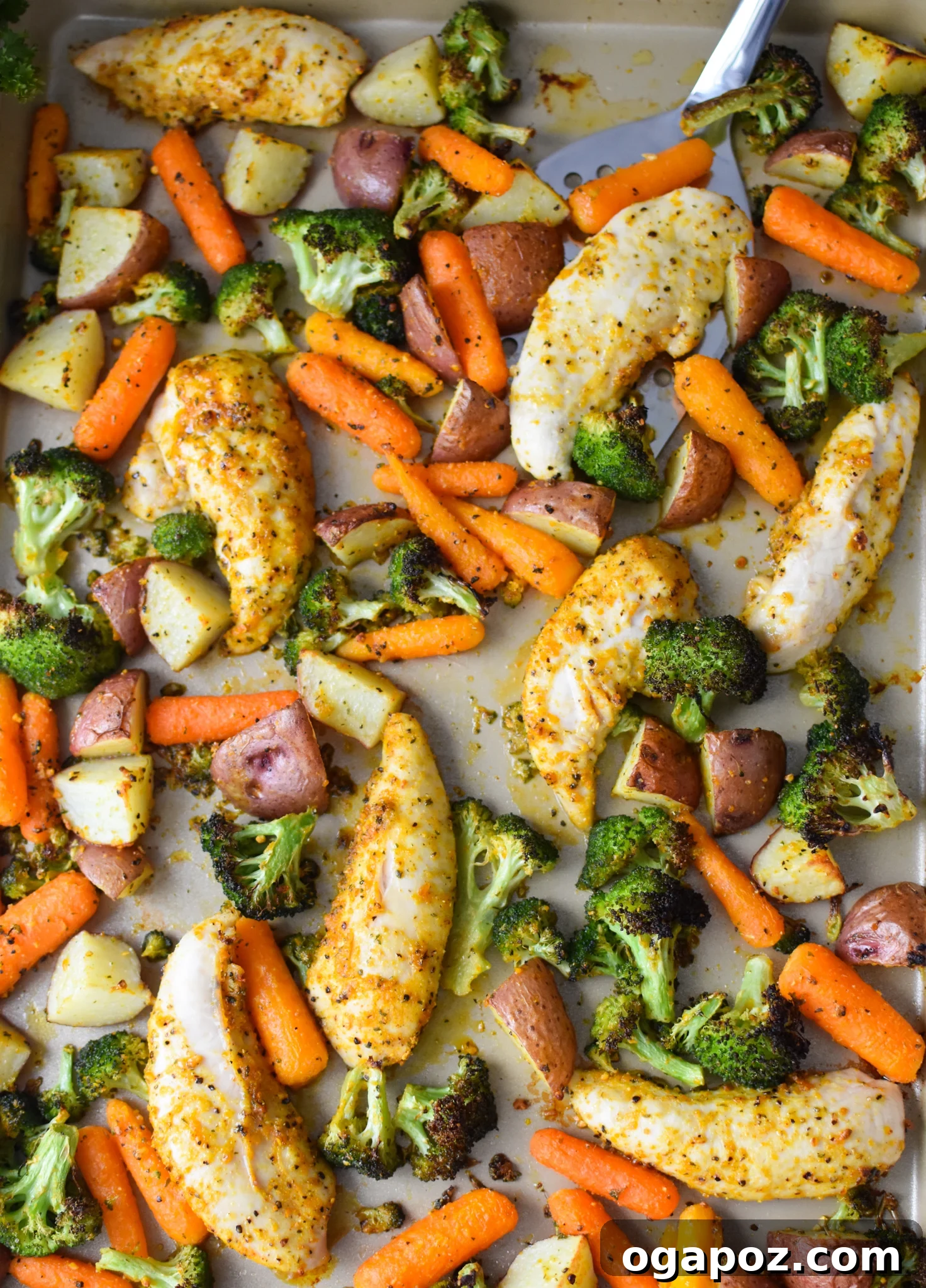 Tek Tepside Limonlu Parmesanlı Tavuk 2 Golden brown Sheet Pan Lemon Parmesan Chicken Tenders with roasted vegetables on a baking sheet, ready to serve.