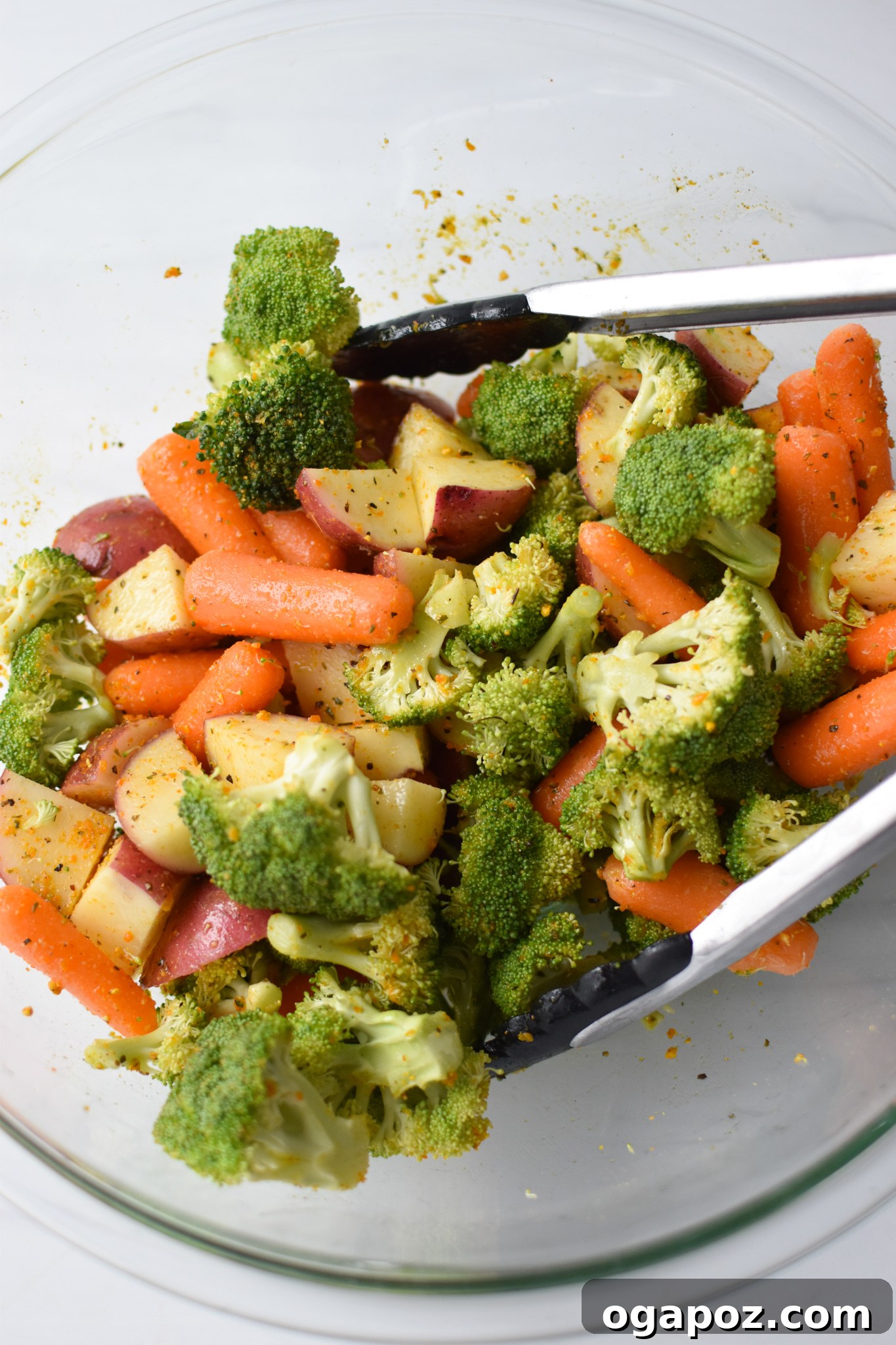 Tek Tepside Limonlu Parmesanlı Tavuk 6 Mixed and seasoned vegetables and potatoes in a bowl, ready to be spread onto a baking sheet for Sheet Pan Lemon Parmesan Chicken Tenders.