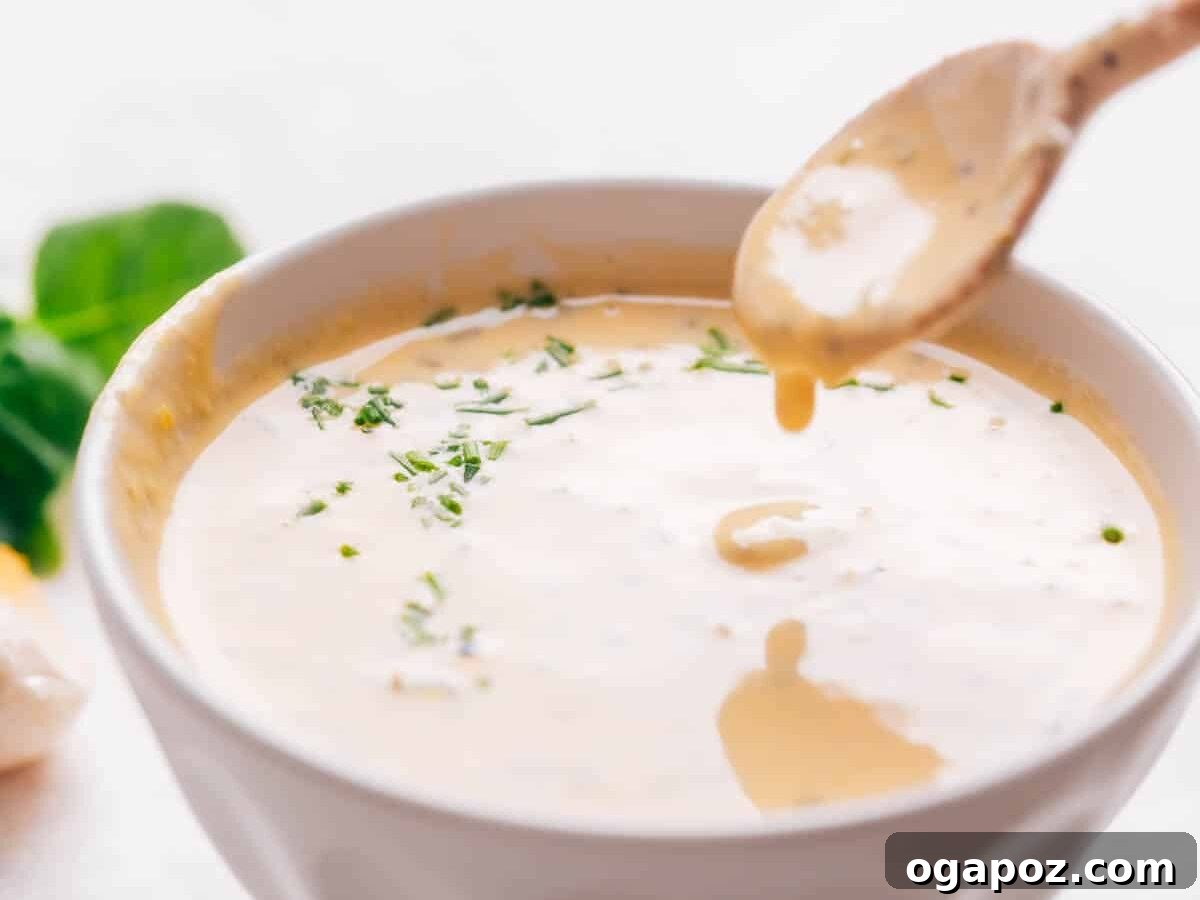 Lemon tahini dressing with a spoon, highlighting its creamy texture.