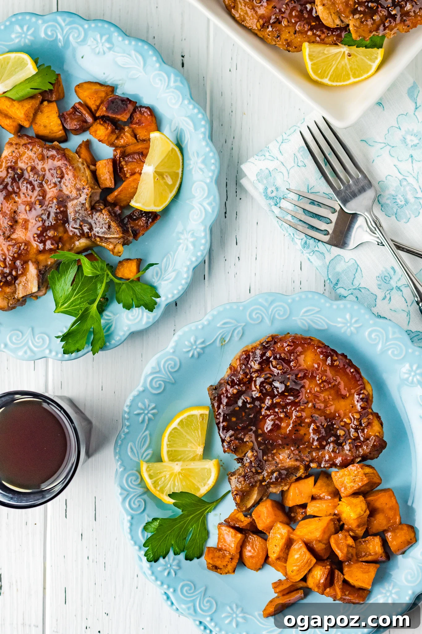Two plates of Maple Bourbon Pork Chops Recipe with sweet potatoes.