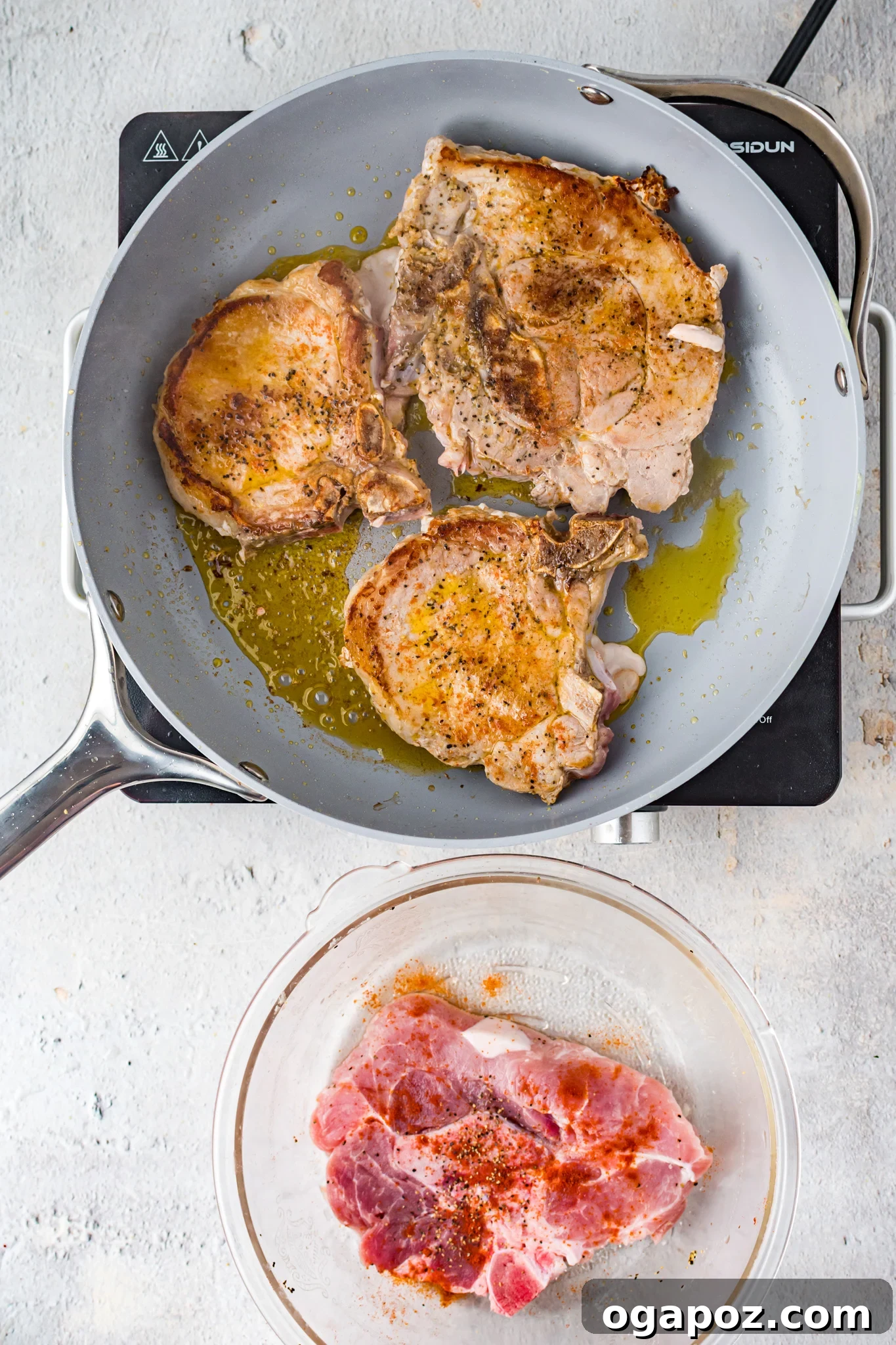 Maple Bourbon Pork Chops Recipe pork chops searing in a skillet.