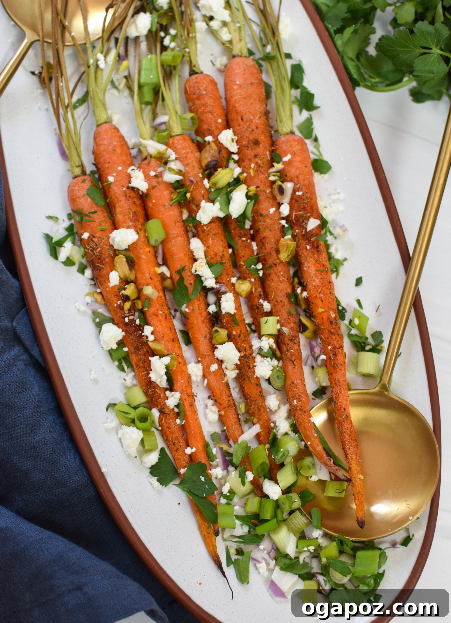 Golden Roasted Carrots with Crunchy Pistachios 4 Roasted Carrots with Pistachios served in a white dish with gold serving spoons.