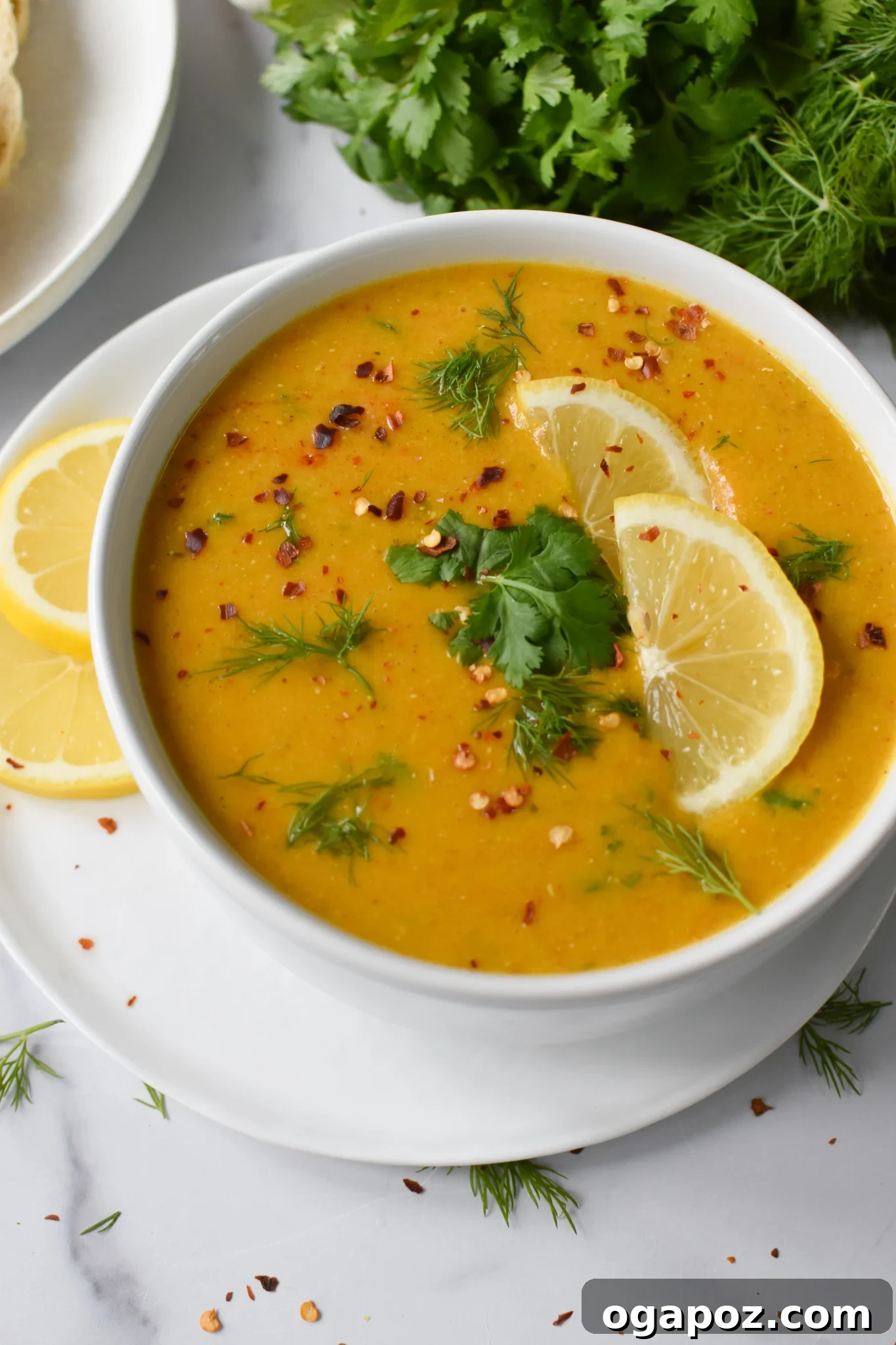 Bright and Zesty Lentil Soup 6 A bowl of Lemon Lentil Soup garnished with fresh cilantro and dill, ready to be served. The vibrant green herbs contrast beautifully with the warm color of the soup.
