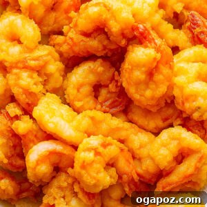 Crispy Fried Cooked Shrimp 9 Crispy fried cooked shrimp garnished with fresh herbs on a serving plate.