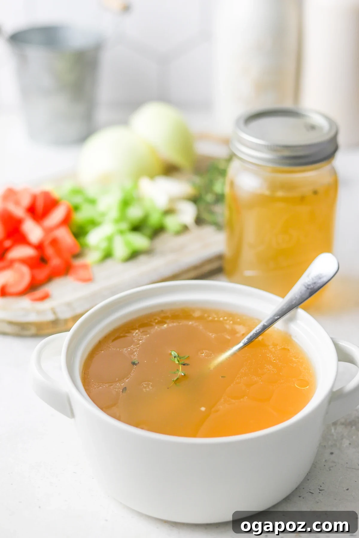 Homemade Chicken Broth in a clear bowl with a spoon, showing its golden hue and inviting warmth.