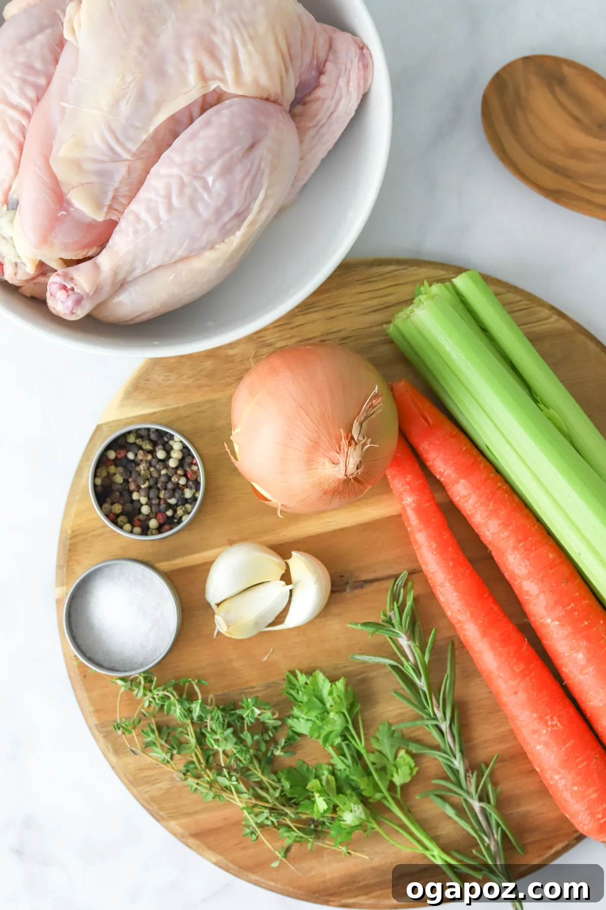 A vibrant selection of ingredients for homemade chicken broth, including a whole chicken, carrots, celery, onion, garlic, and fresh herbs.