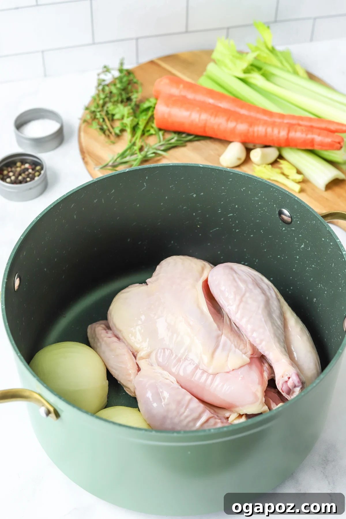 A whole chicken and chopped vegetables browning in a large stockpot, showcasing the initial step in homemade broth preparation.