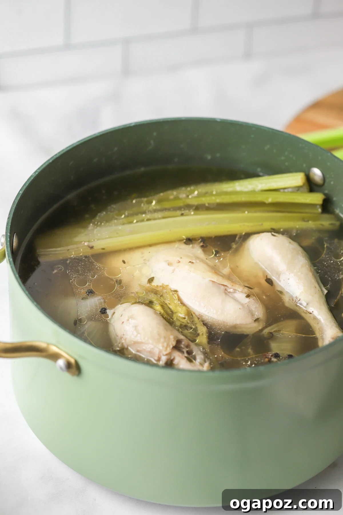 A stockpot filled with chicken, vegetables, water, and herbs, beginning the long simmering process for homemade chicken broth.