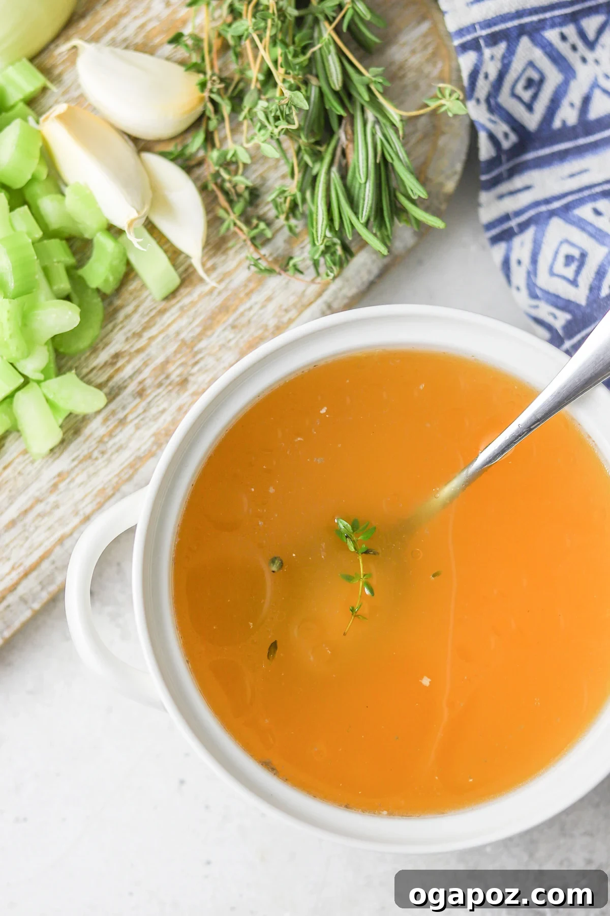 A white bowl of Homemade Chicken Broth with a spoon, highlighting its inviting readiness.