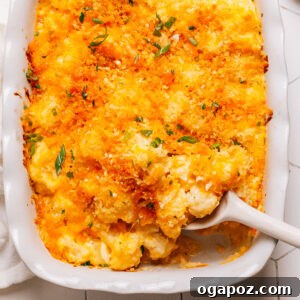 Cauliflower casserole in a baking dish with a spoon, showing its creamy interior and crispy topping.