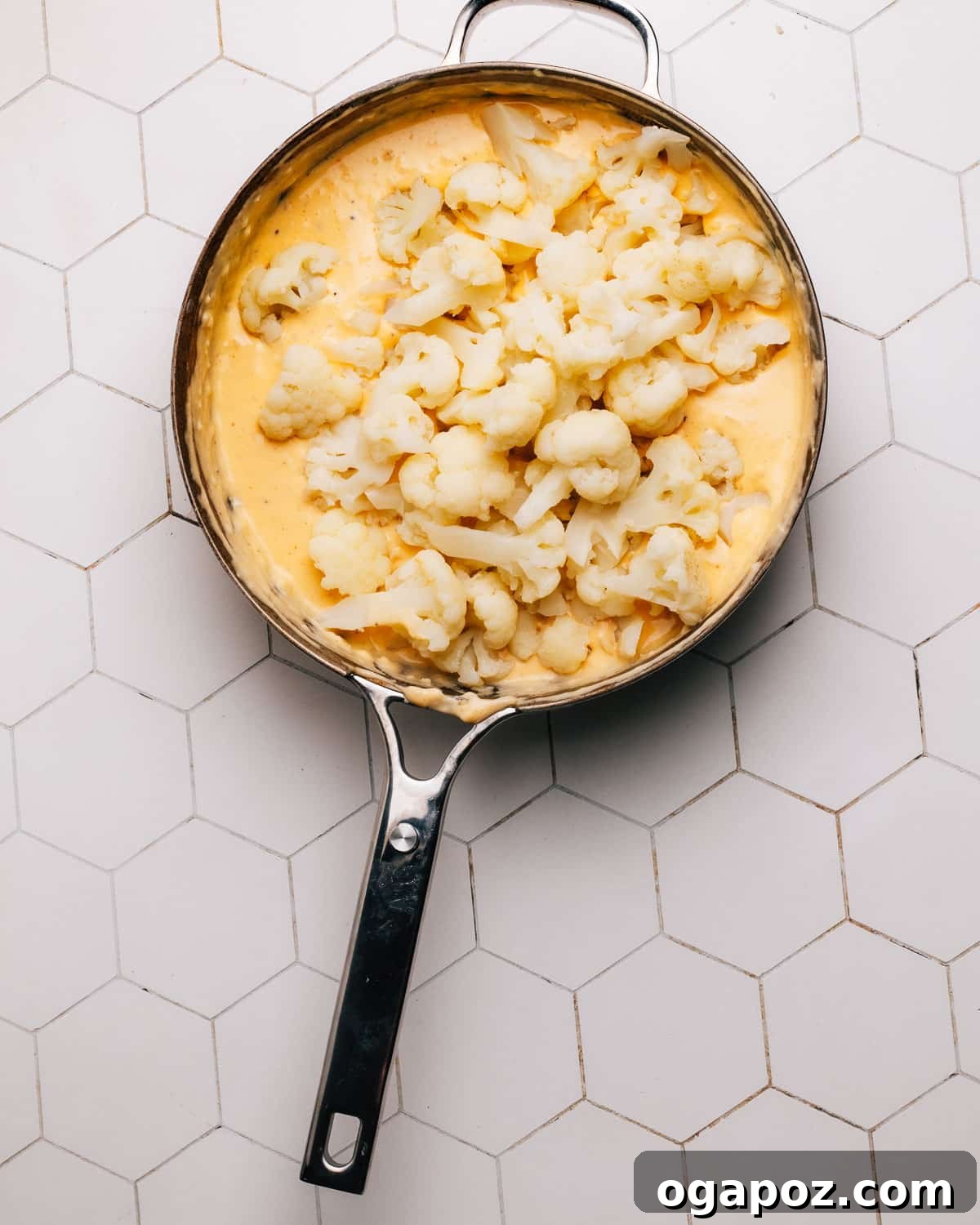 The cauliflower and cheese mixture being transferred into a prepared baking dish, ready for the topping.