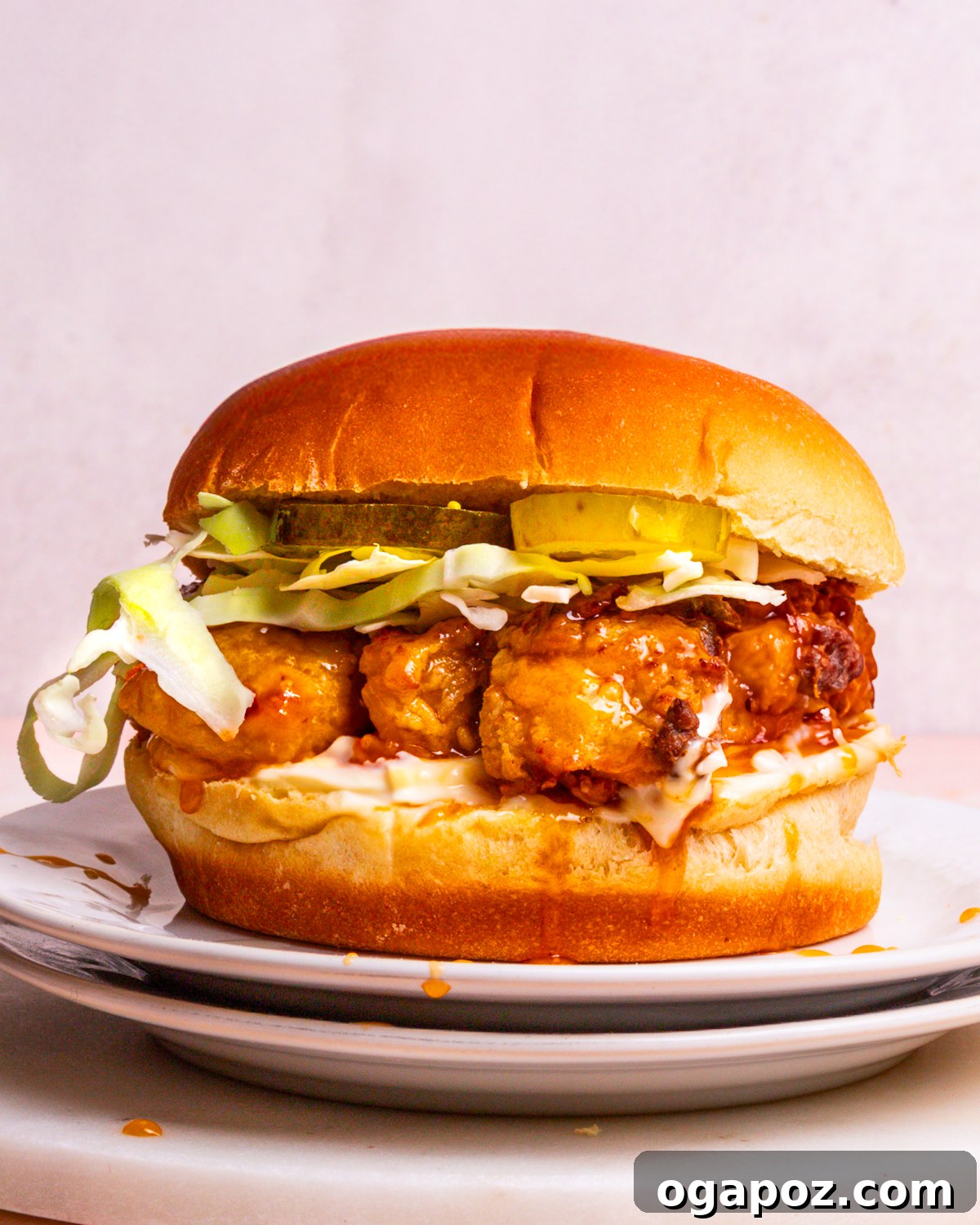 Crispy Sweet Heat Chicken Sandwich 2 A perfectly assembled hot honey chicken sandwich on a plate, showcasing its golden crispy chicken, sweet sauce, and tangy pickles.