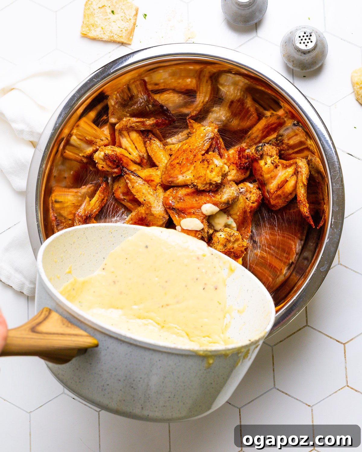 Bold Garlic Parmesan Sauce 5 Pouring rich garlic parmesan sauce over crispy chicken wings.