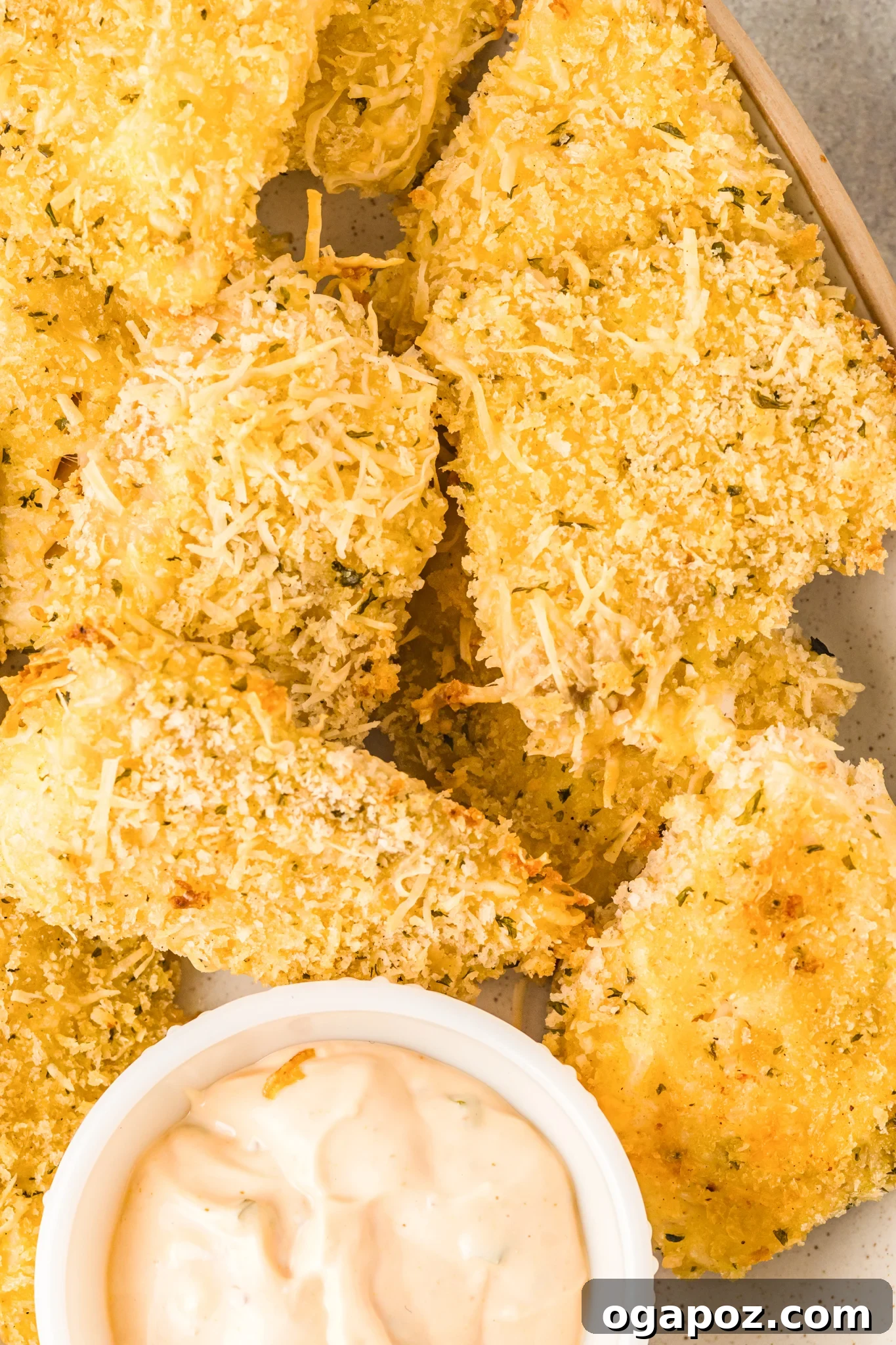 Baked Parmesan Fish Sticks served with a creamy dip in a bowl.