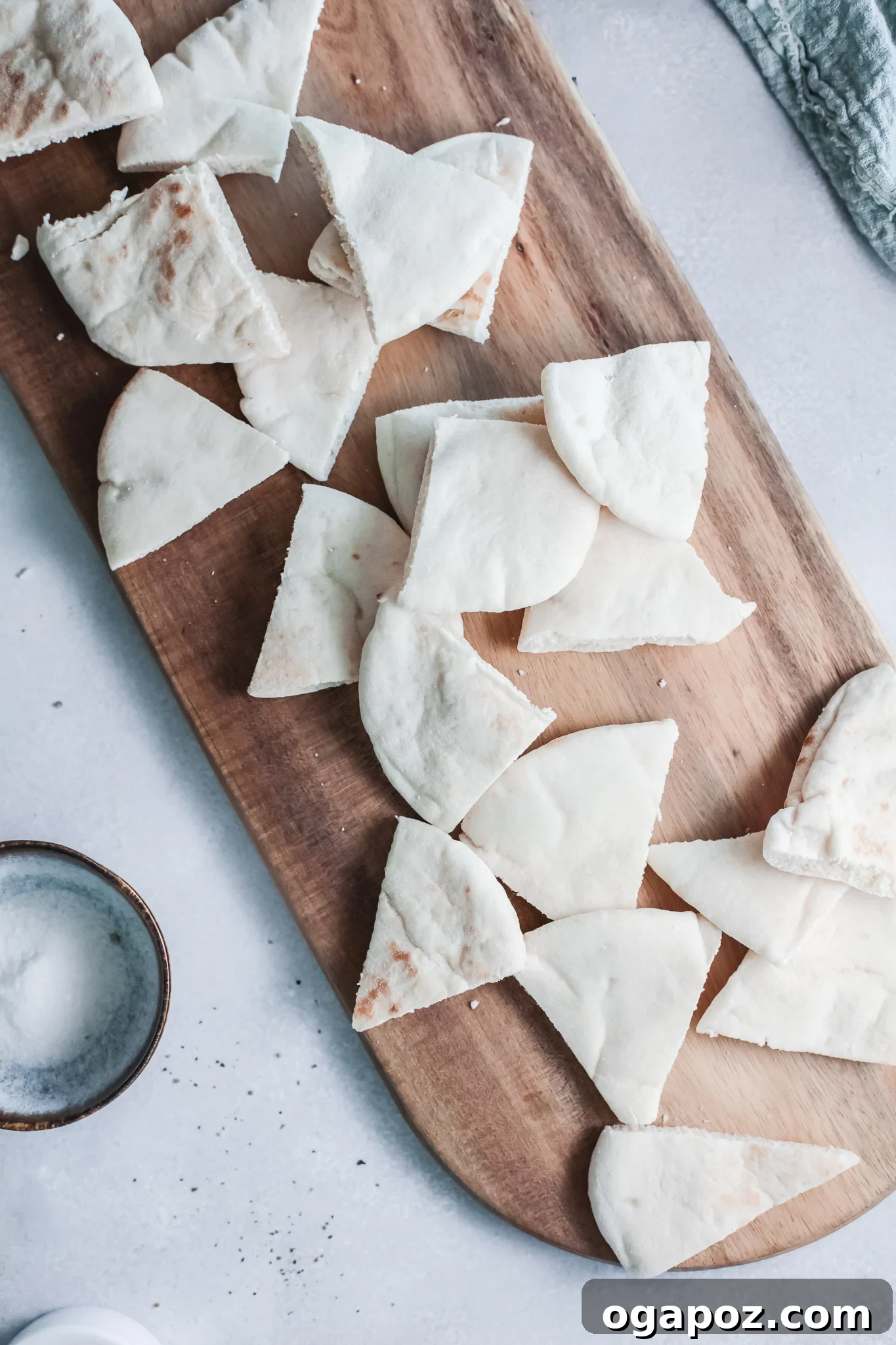 Crispy Air Fryer Pita Chips 5 Pita bread being cut into triangles on a wooden cutting board.