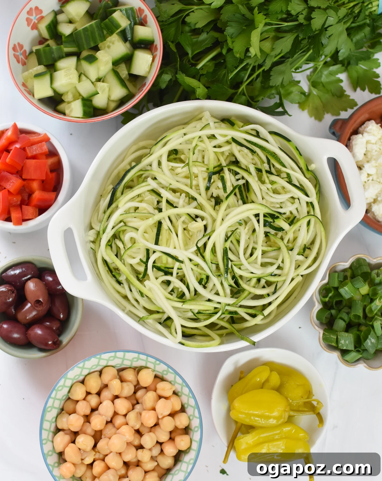 Vibrant Mediterranean Zucchini Pasta Salad 3 A collection of fresh ingredients laid out, including zucchini, chickpeas, cucumbers, tomatoes, bell peppers, olives, and feta cheese, ready for the Mediterranean Zucchini Pasta Salad.