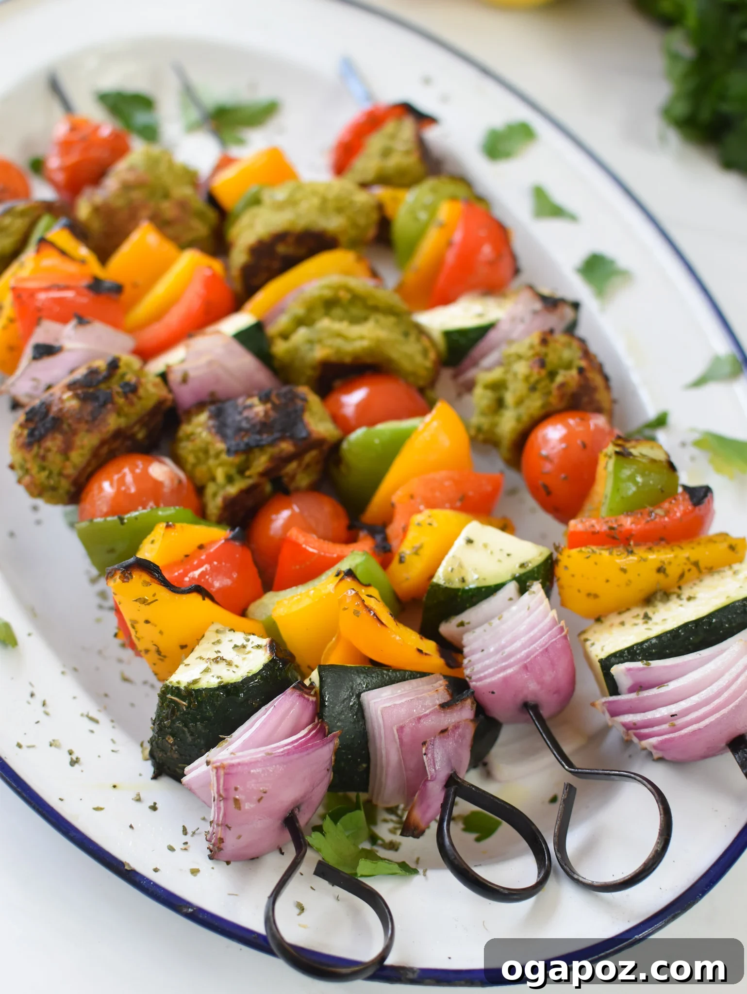Mediterranean Falafel & Veggie Skewers 9 Beautifully plated Falafel Vegetable Kabobs, fresh off the grill, served on a white platter with a garnish of fresh herbs.
