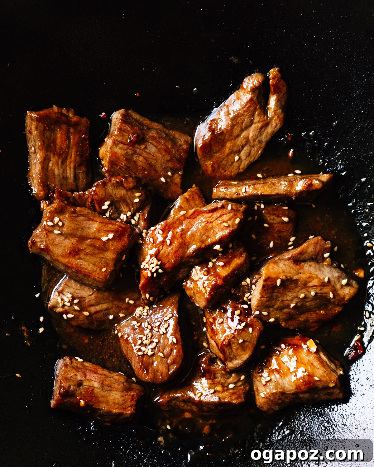 Slices of beef teriyaki sizzling and browning in a hot skillet during the cooking process.