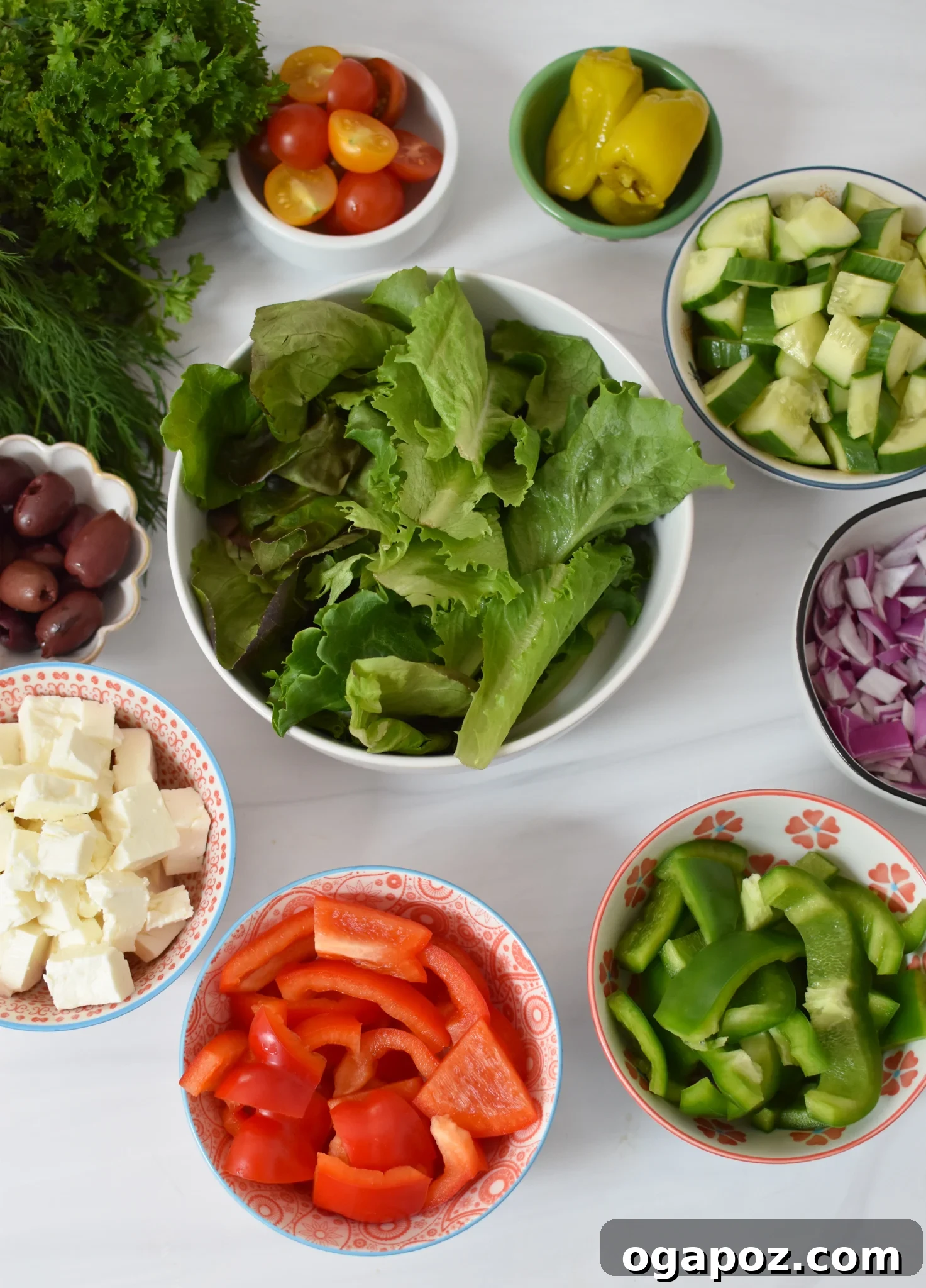 Fresh ingredients for Grilled Chicken Greek Salad laid out on a white surface.