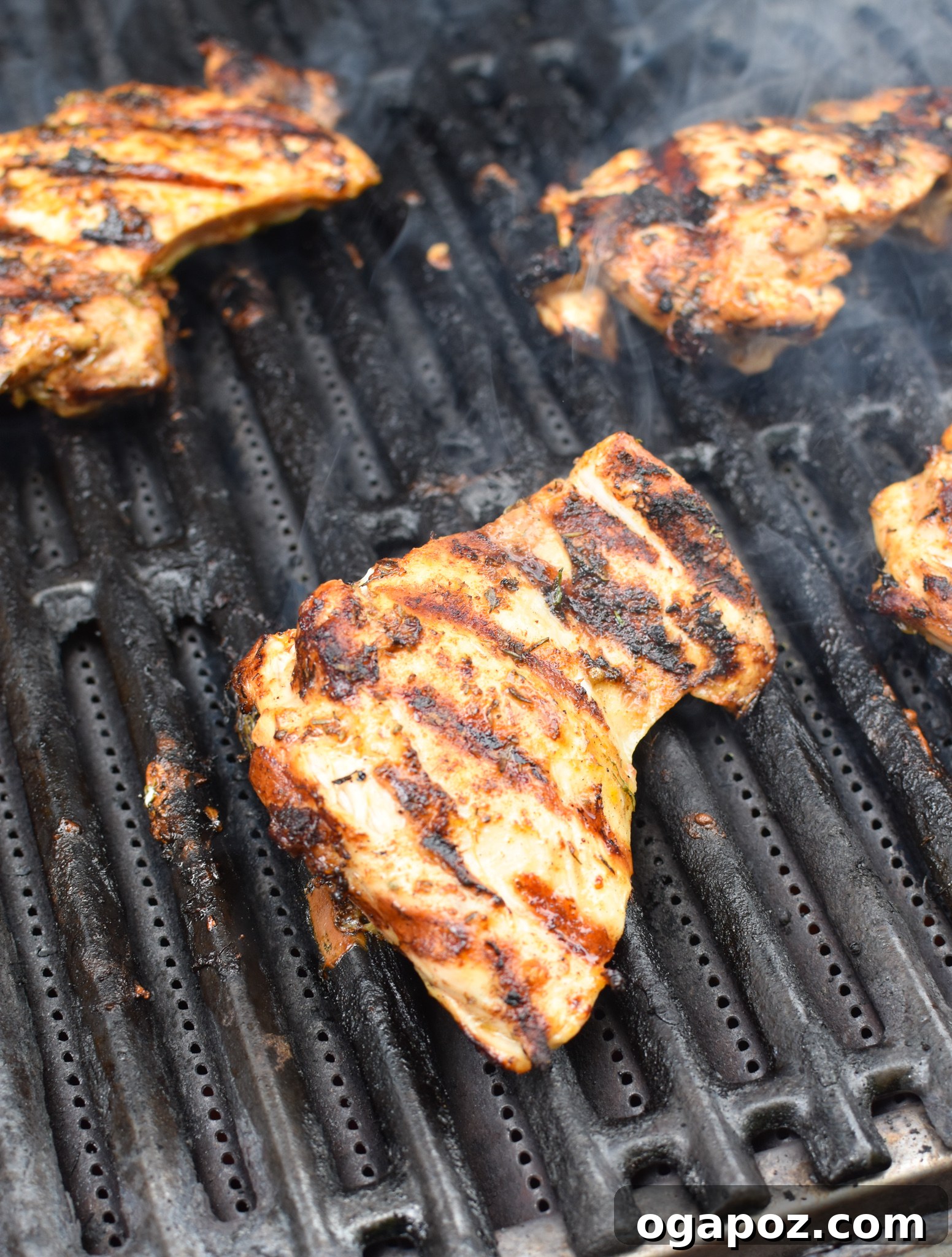 Chicken thighs sizzling on a hot grill, showing perfect char marks.