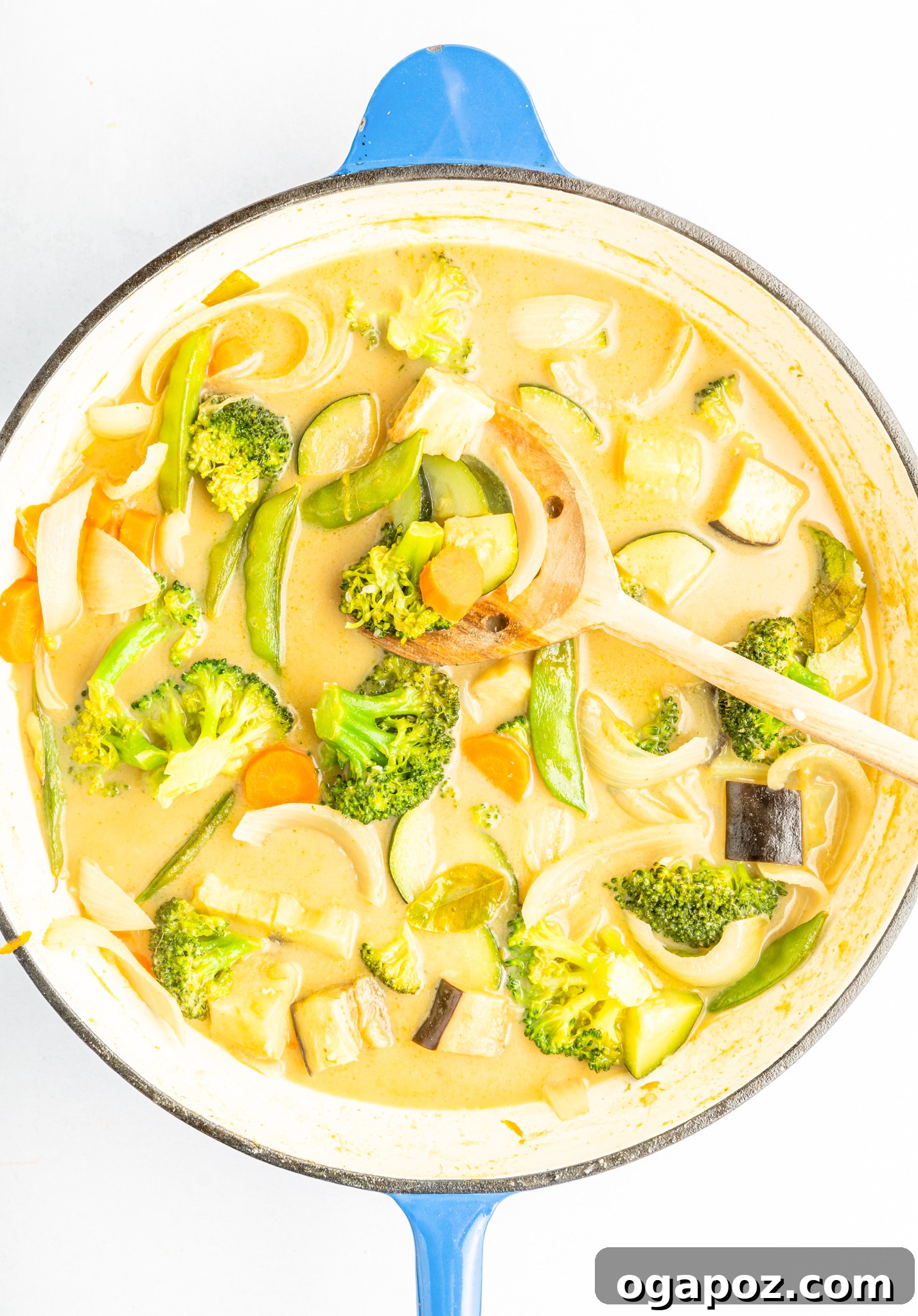 Quick & Delicious Thai Veggie Green Curry 7 A close-up shot of a spoon being used to stir and check the consistency and doneness of the Thai Vegetable Green Curry, showcasing the creamy sauce and tender vegetables.