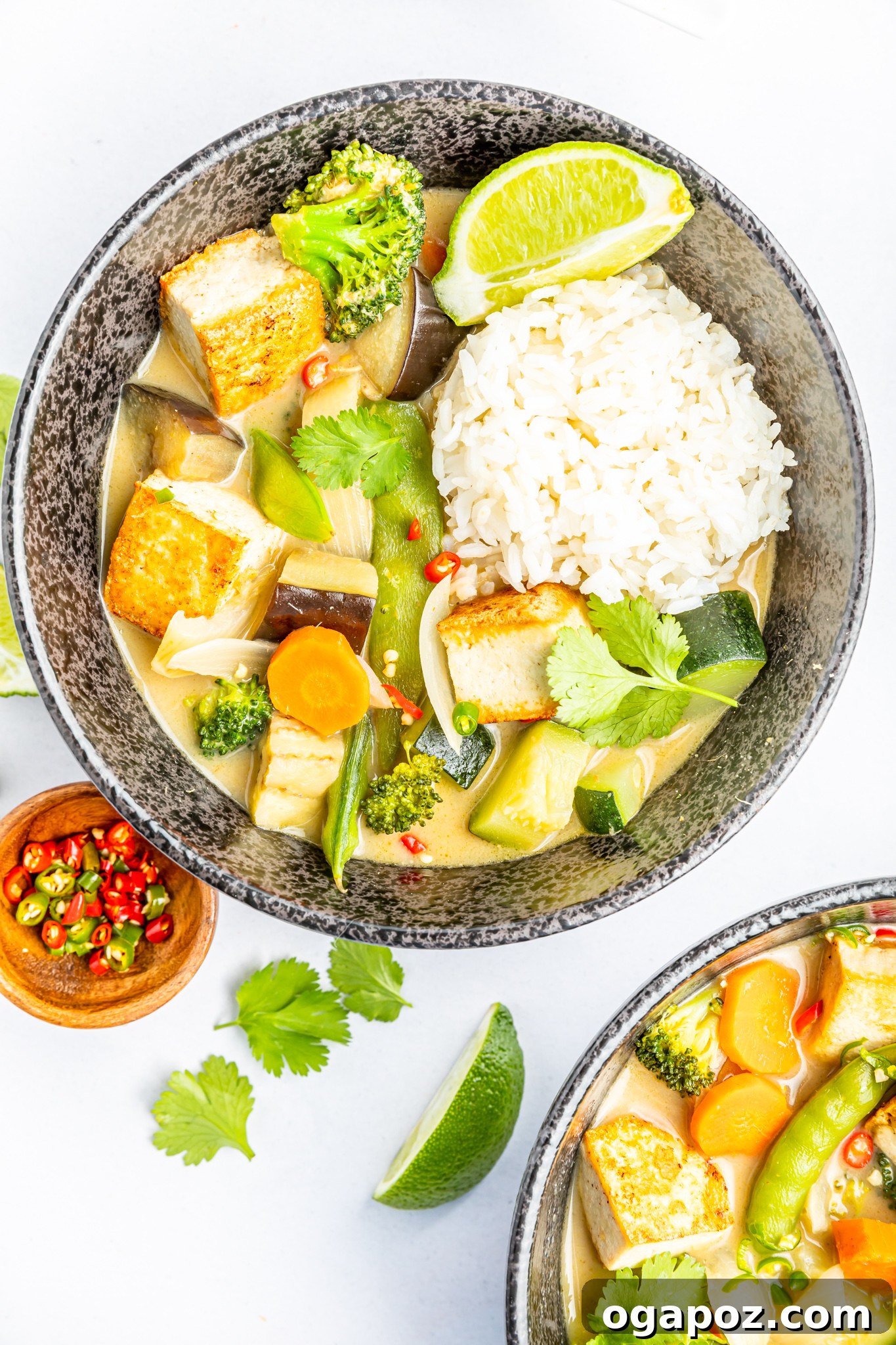 Quick & Delicious Thai Veggie Green Curry 8 A beautifully presented bowl of Thai Vegetable Green Curry accompanied by a side of fluffy steamed jasmine rice, garnished generously with fresh cilantro.
