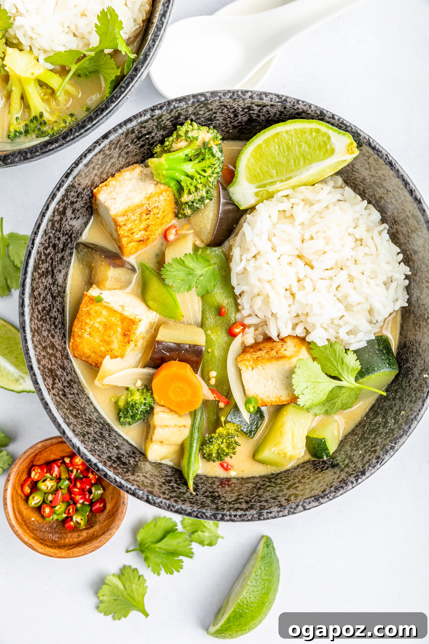 Quick & Delicious Thai Veggie Green Curry 9 A bowl of vibrant Thai Vegetable Green Curry presented with fresh lime wedges on the side, ready for serving and an extra touch of citrus.