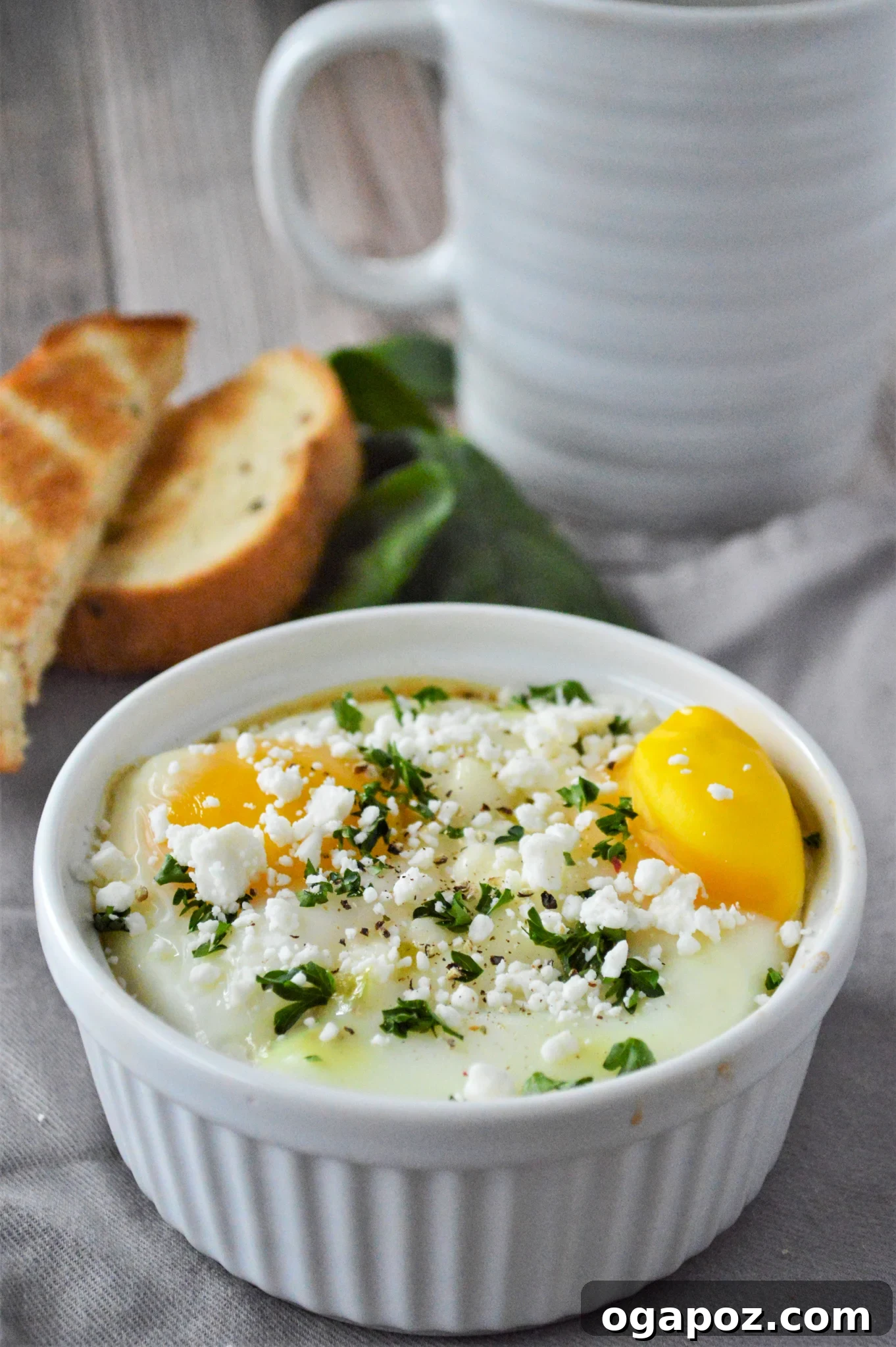 Rustic Greek Egg Bake 11 A close-up of Greek Baked Eggs in a white ramekin, garnished with parsley.