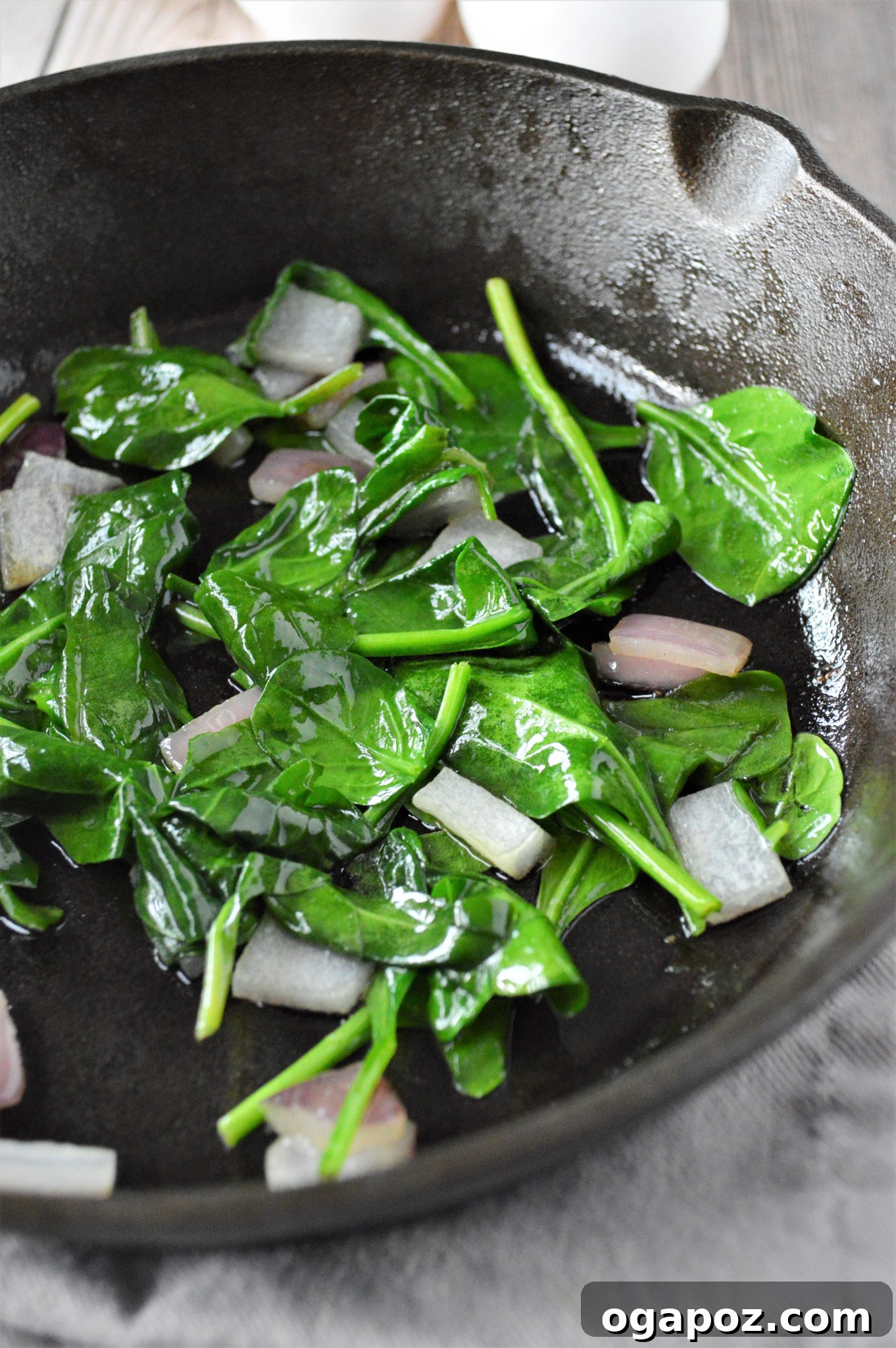 Rustic Greek Egg Bake 5 Spinach wilting in a skillet with red onion for Greek Baked Eggs.