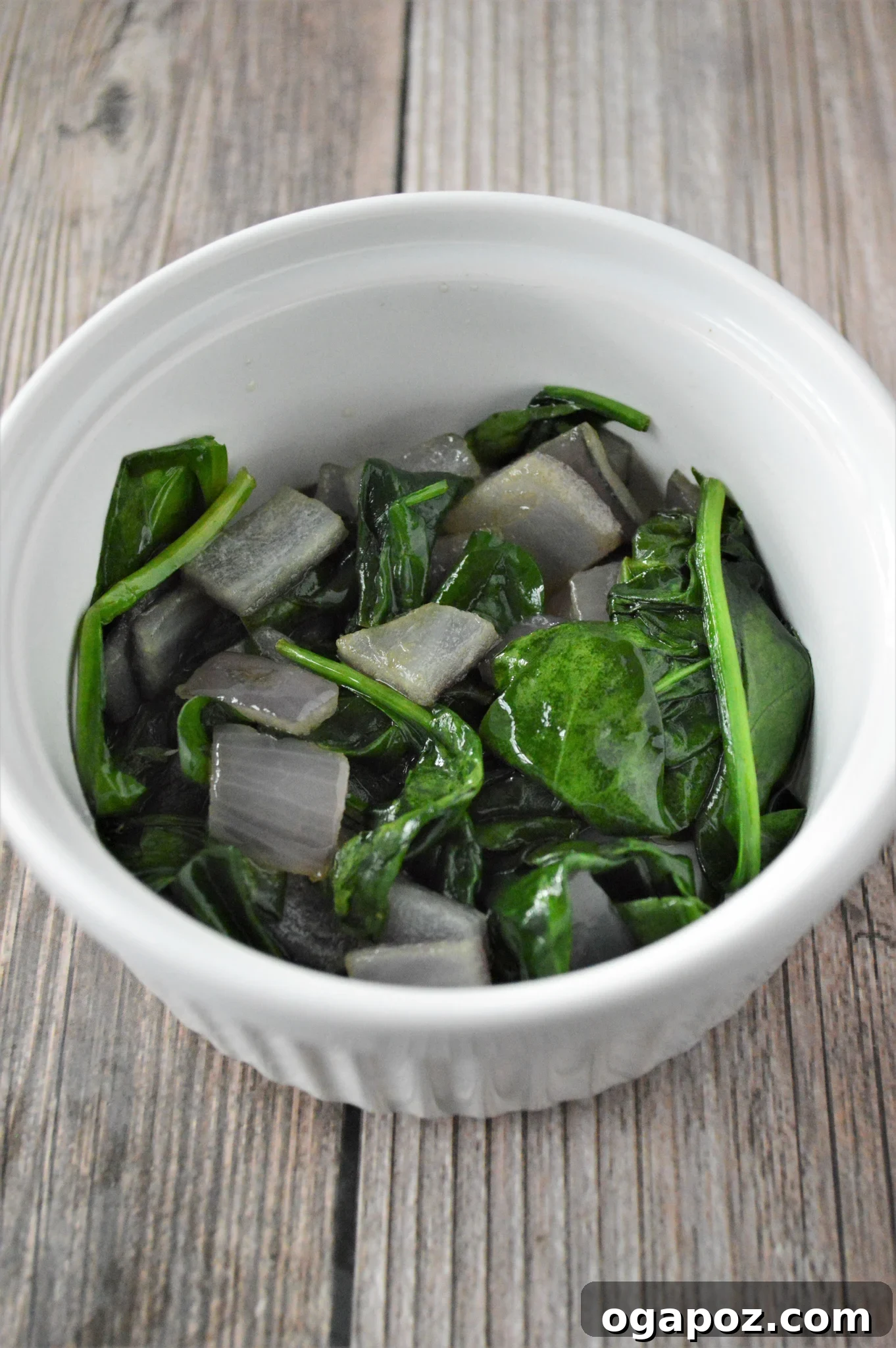 Rustic Greek Egg Bake 6 Sautéed spinach and onion placed at the bottom of a ramekin.