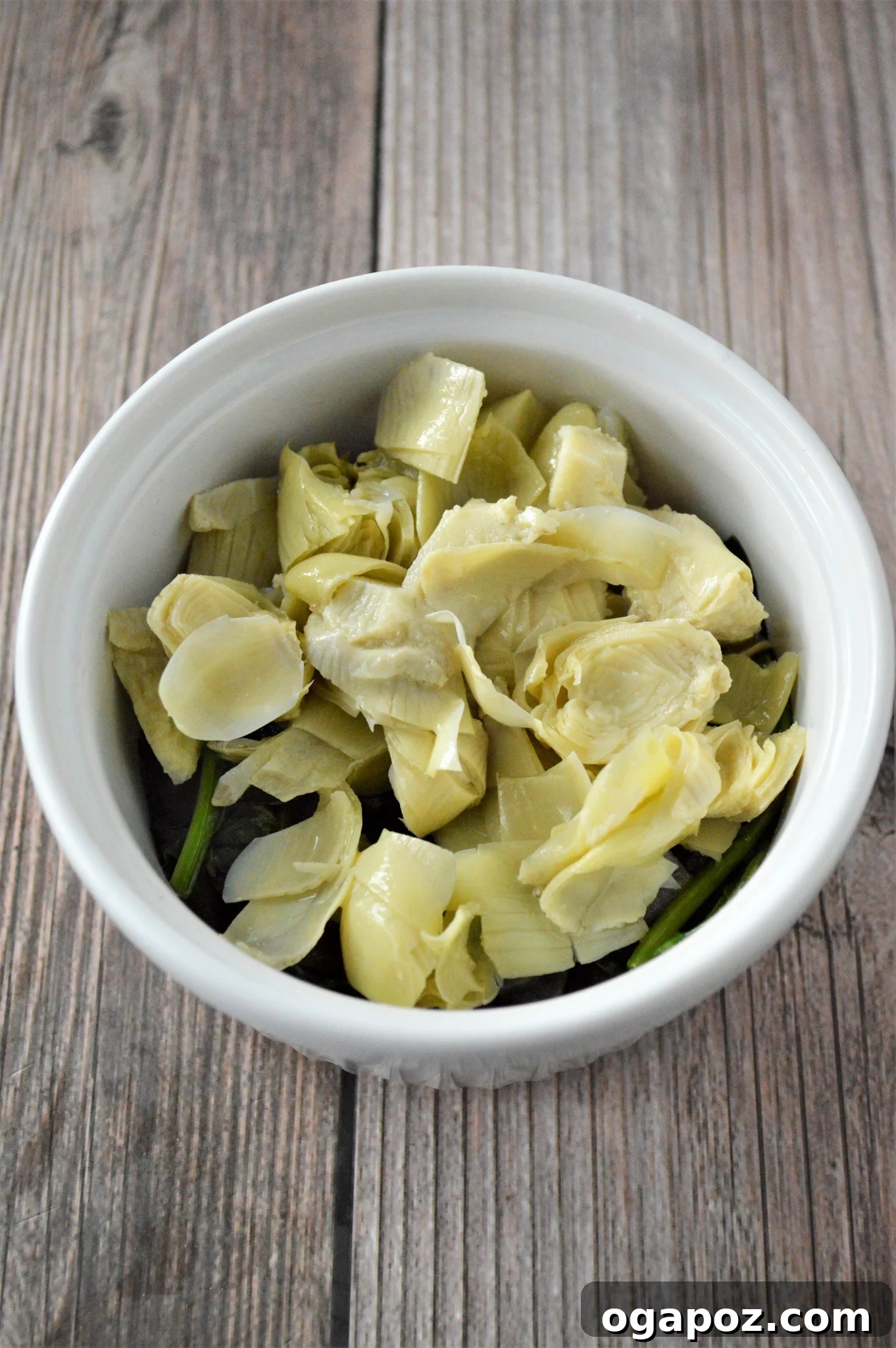 Rustic Greek Egg Bake 7 Chopped artichoke hearts layered over spinach and onion in a ramekin.
